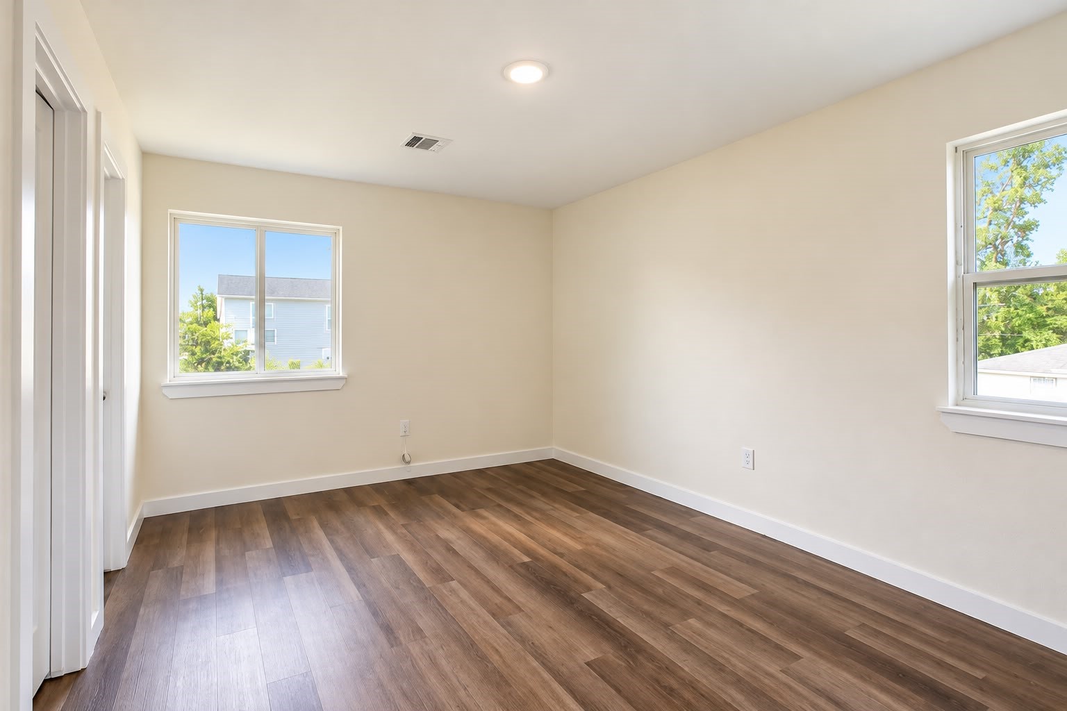 Bright bedroom with two windows and recessed lighting.