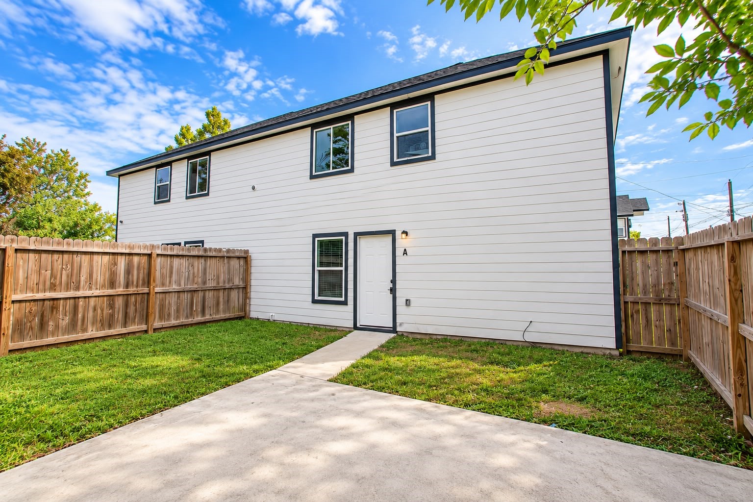 Private fenced backyard with a walkway to the back door.
