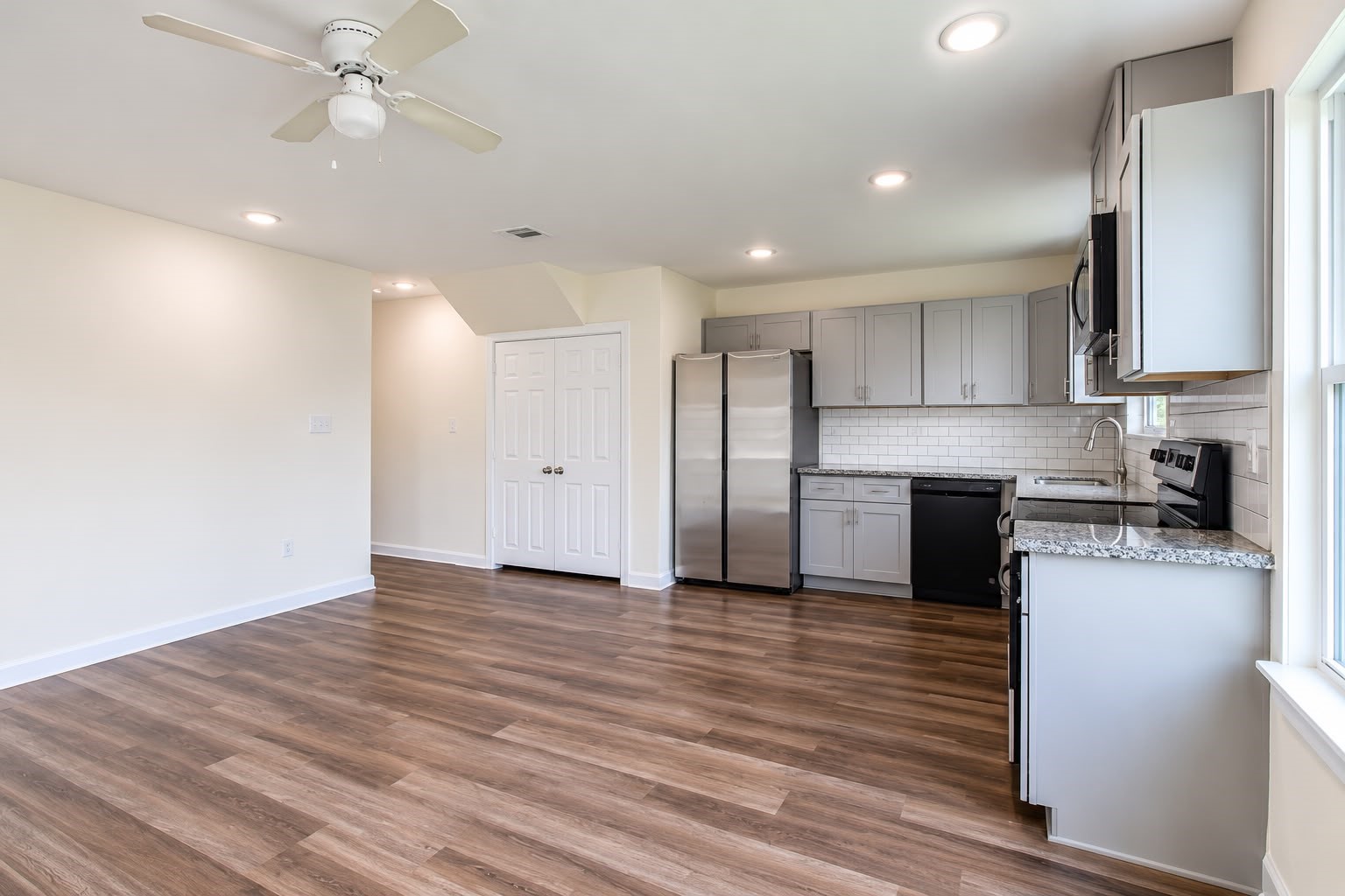 Kitchen with stainless steel appliances, gray cabinets, and plenty of counter space, open to the living area.