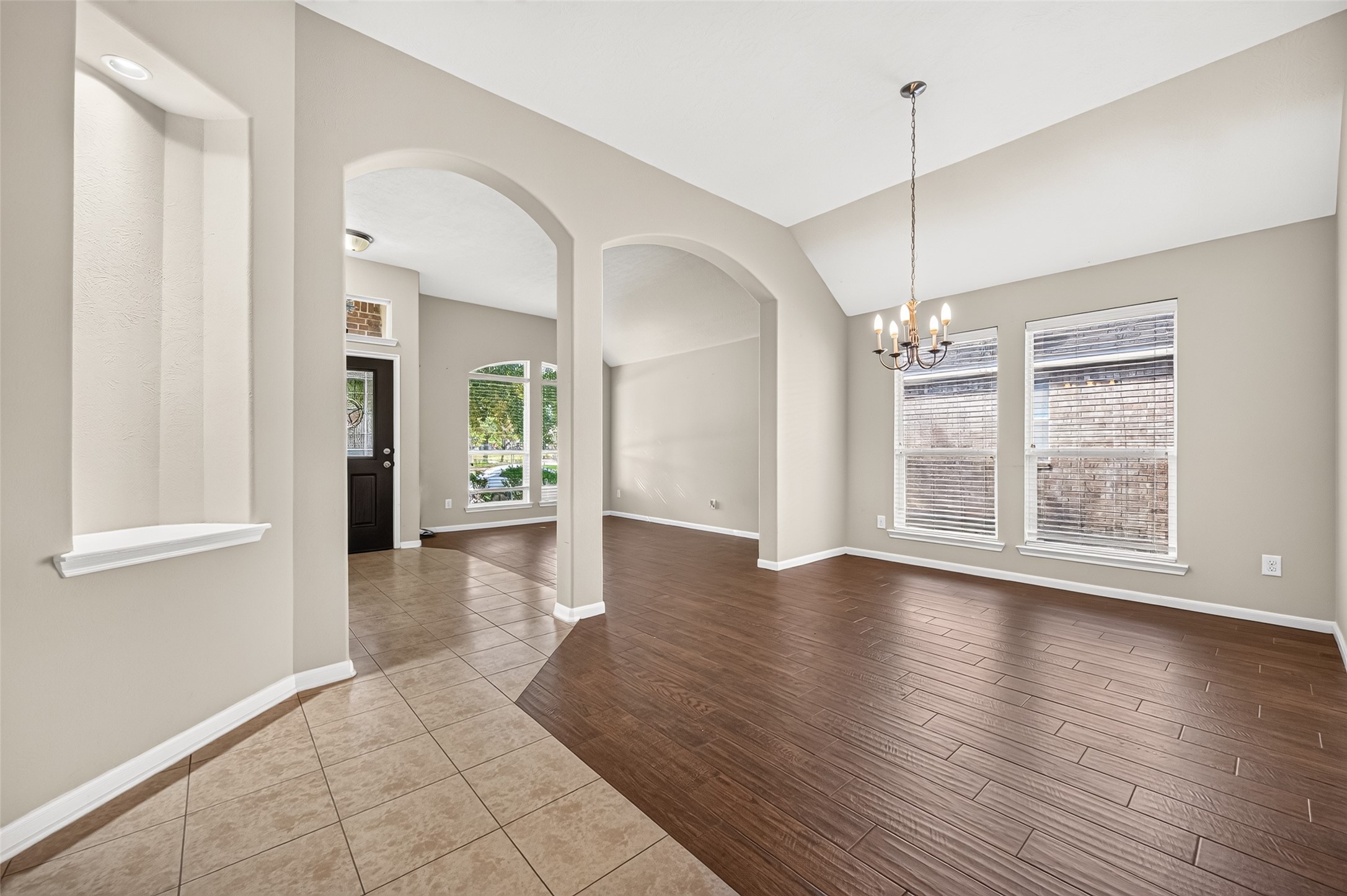 Bright entryway featuring arched openings, neutral walls, and a combination of tile and wood-look flooring.