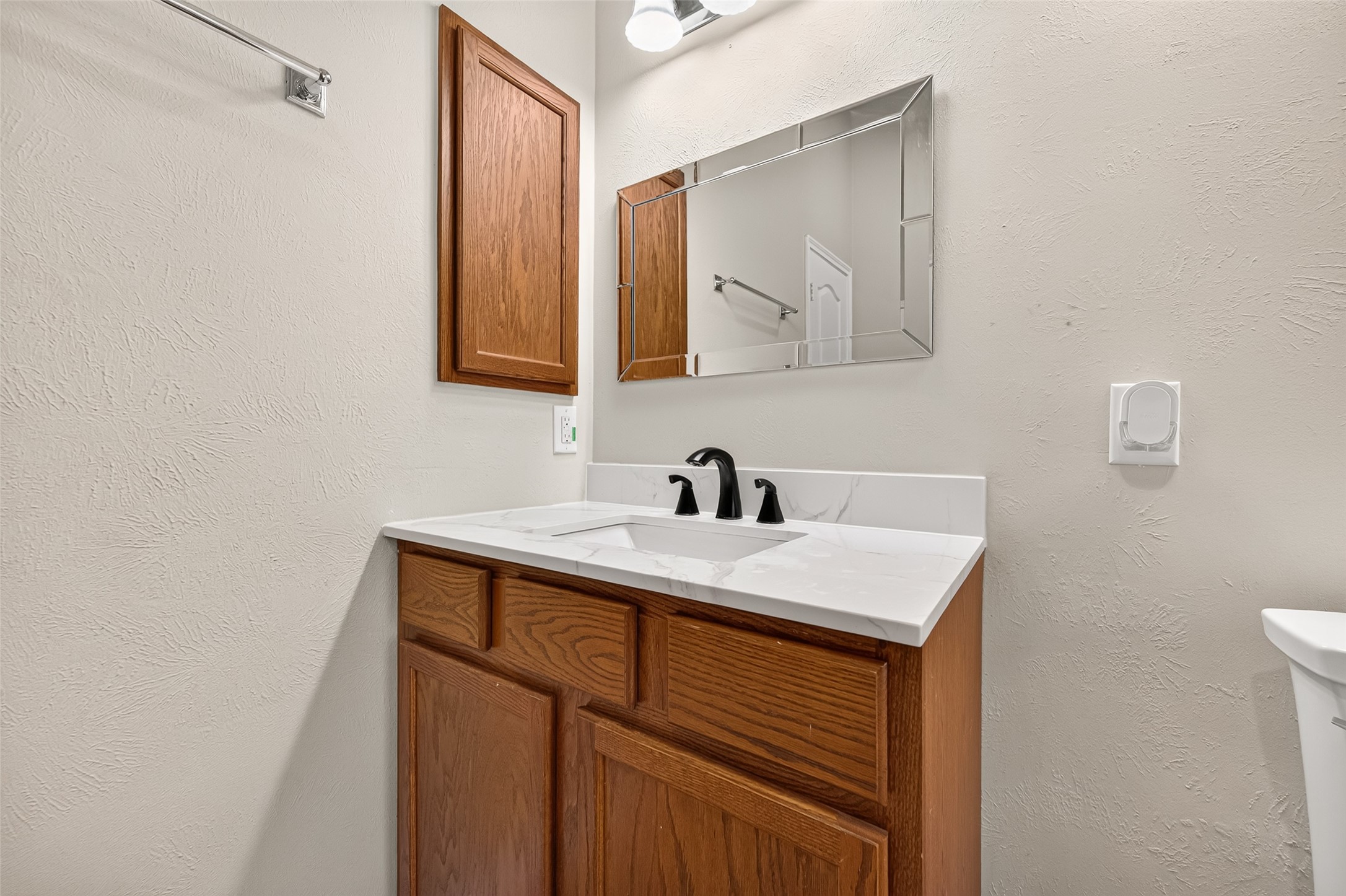 Bathroom vanity area featuring wood cabinetry, a countertop sink, and a wall-mounted mirror.