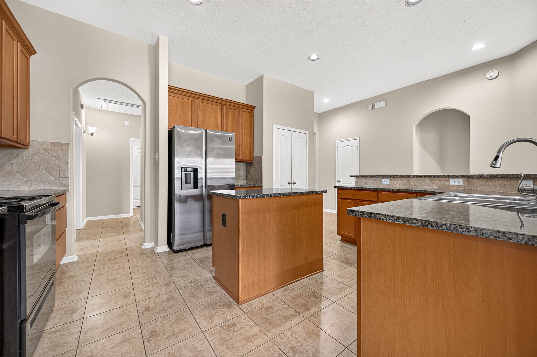 View from the kitchen showcasing the open layout, arched architectural details, and adjacent living spaces.