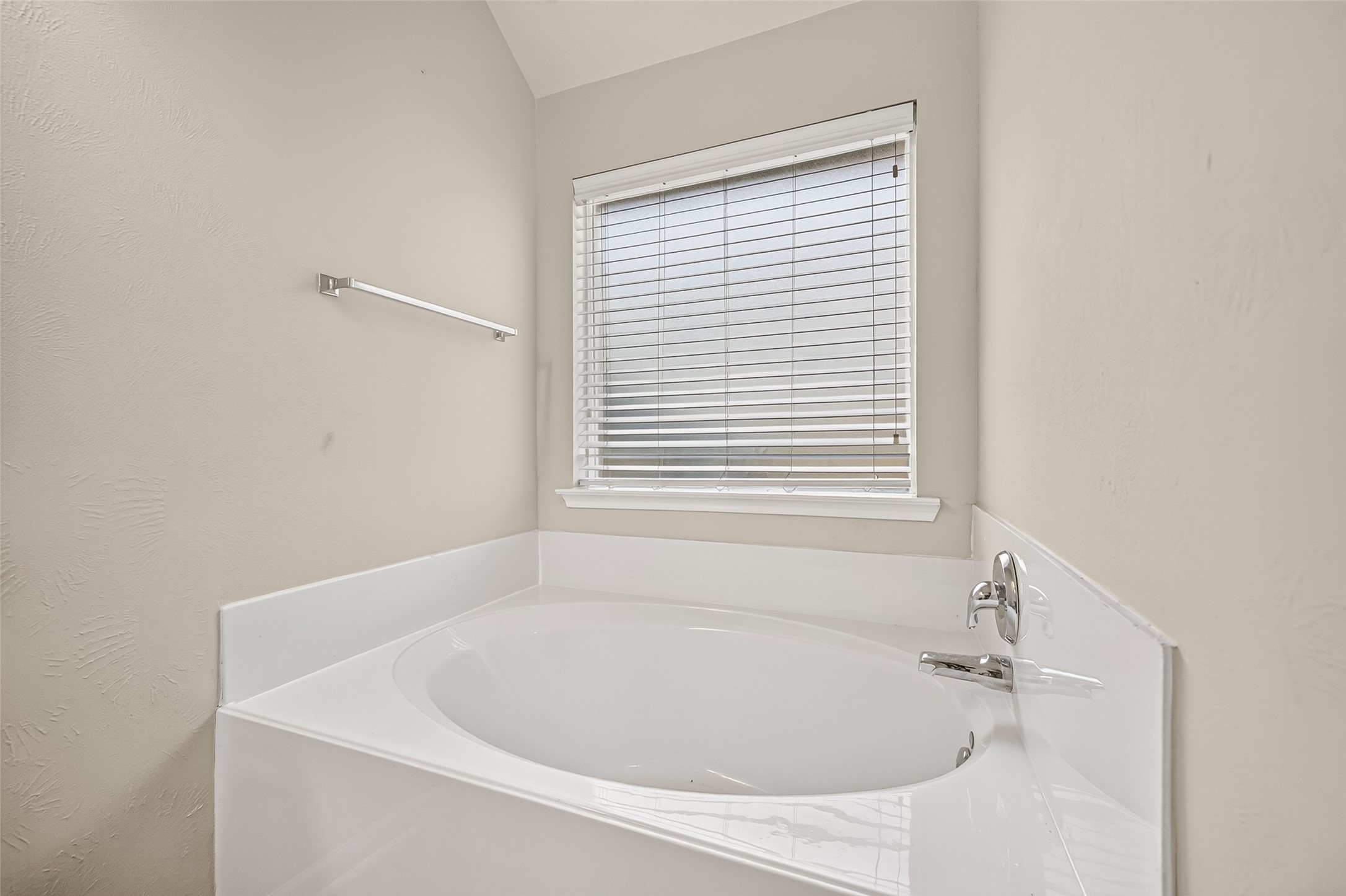Separate soaking tub positioned beneath a window, offering natural light and a relaxing bathroom setting.