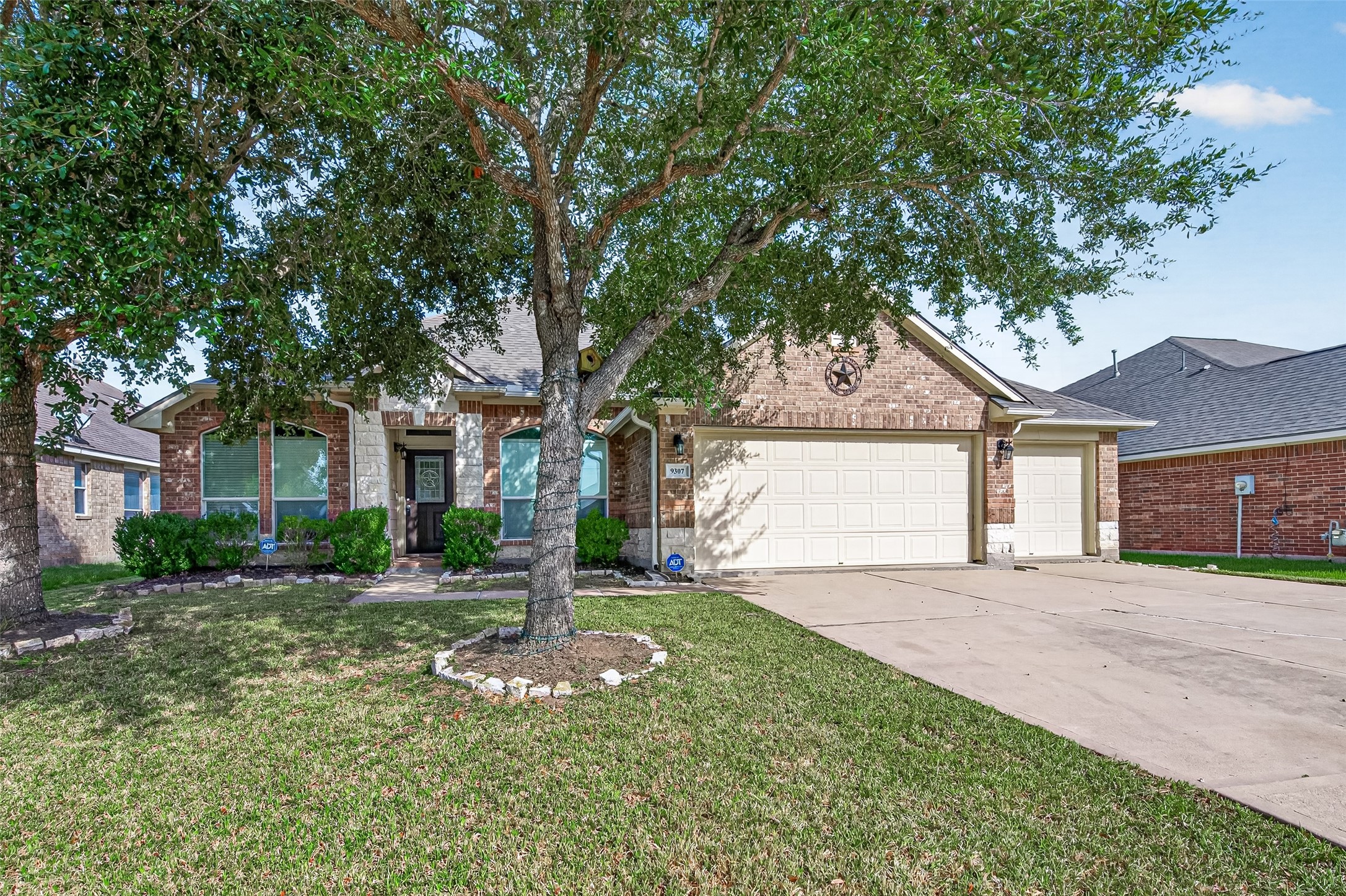 Front exterior featuring brick construction, mature landscaping, and an arched covered entrance.