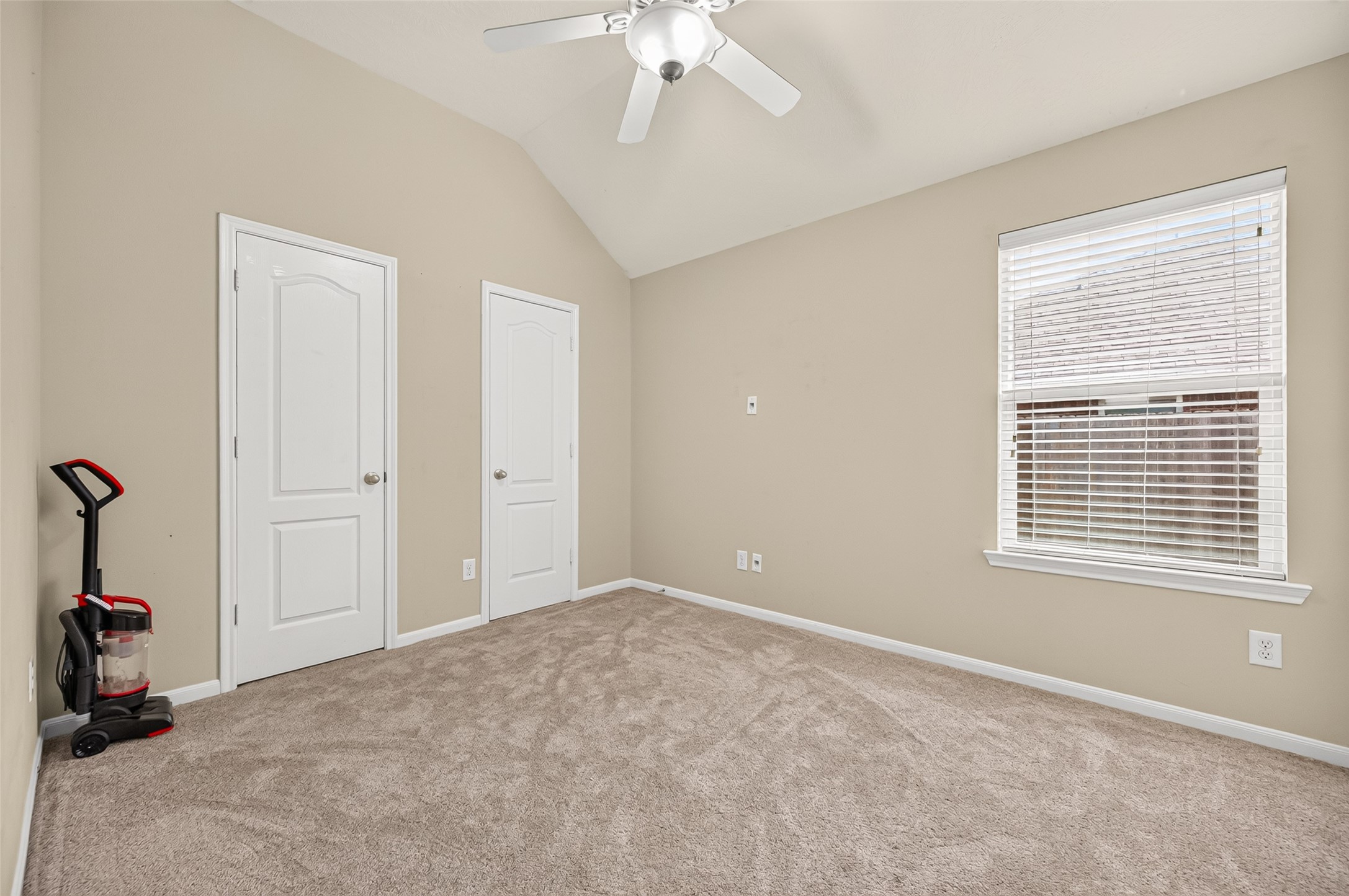 Secondary bedroom featuring a vaulted ceiling, neutral carpeting, and convenient access to the hallway