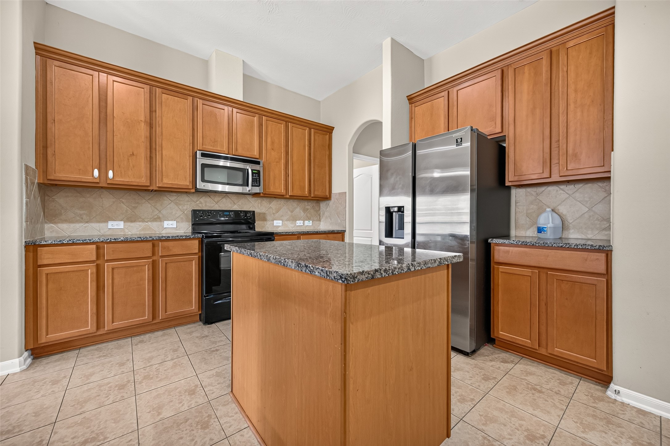 Kitchen featuring a center island, generous counter space, wood cabinetry, and tile flooring.