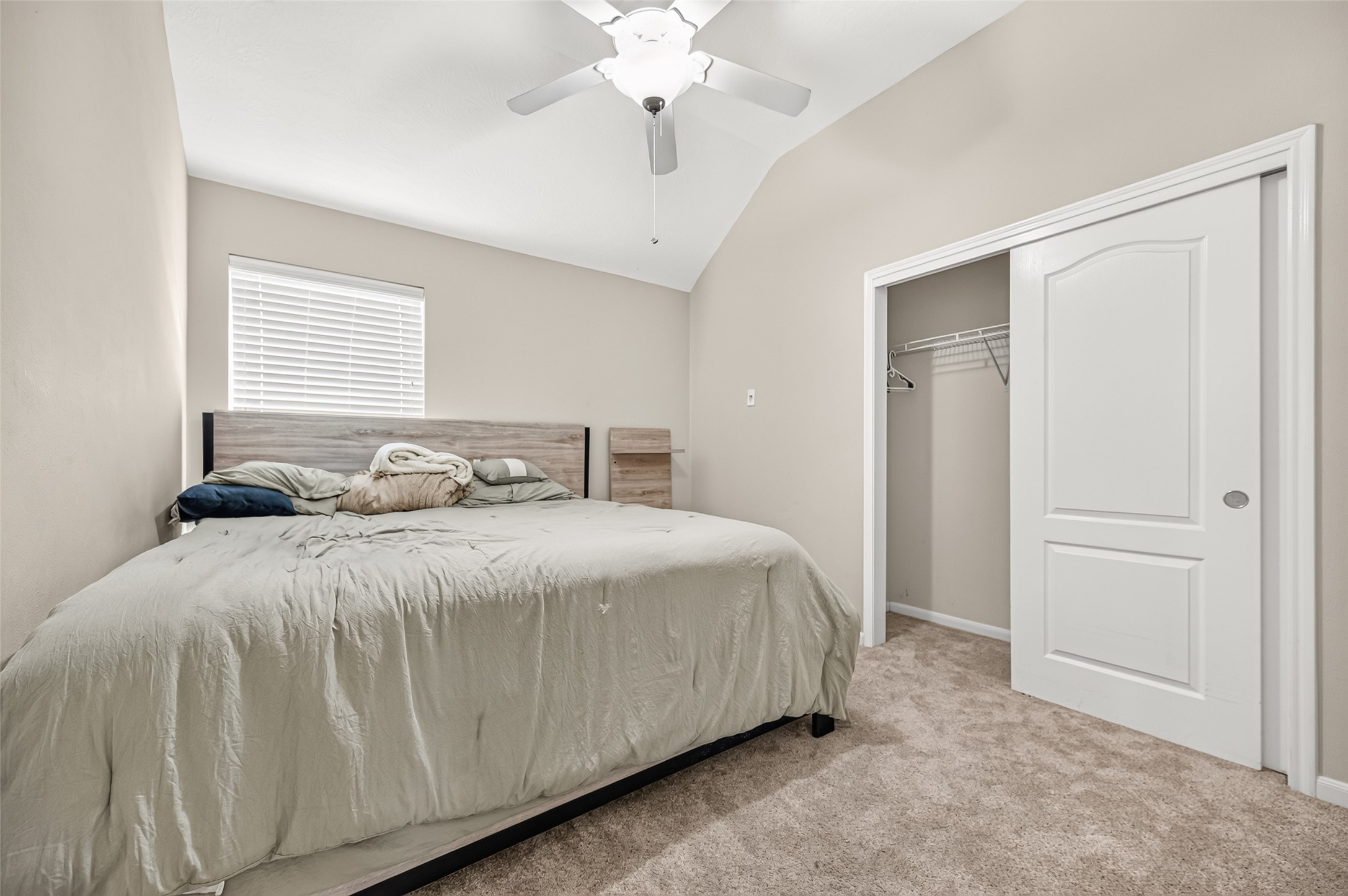 Secondary bedroom featuring neutral carpeting, ceiling fan, and a window overlooking the exterior.