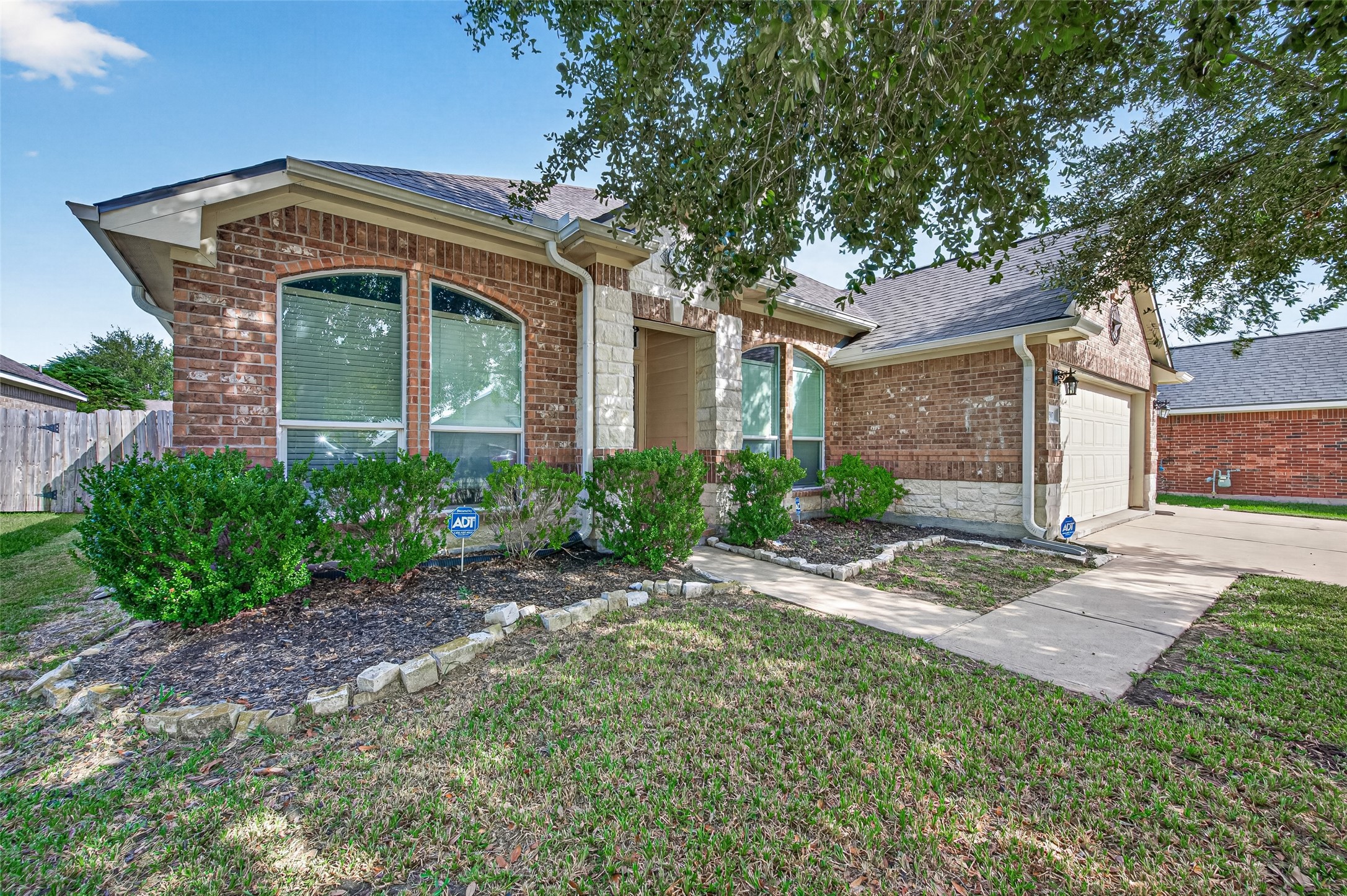 Additional backyard perspective highlighting the mature tree, fenced perimeter, and open lawn.