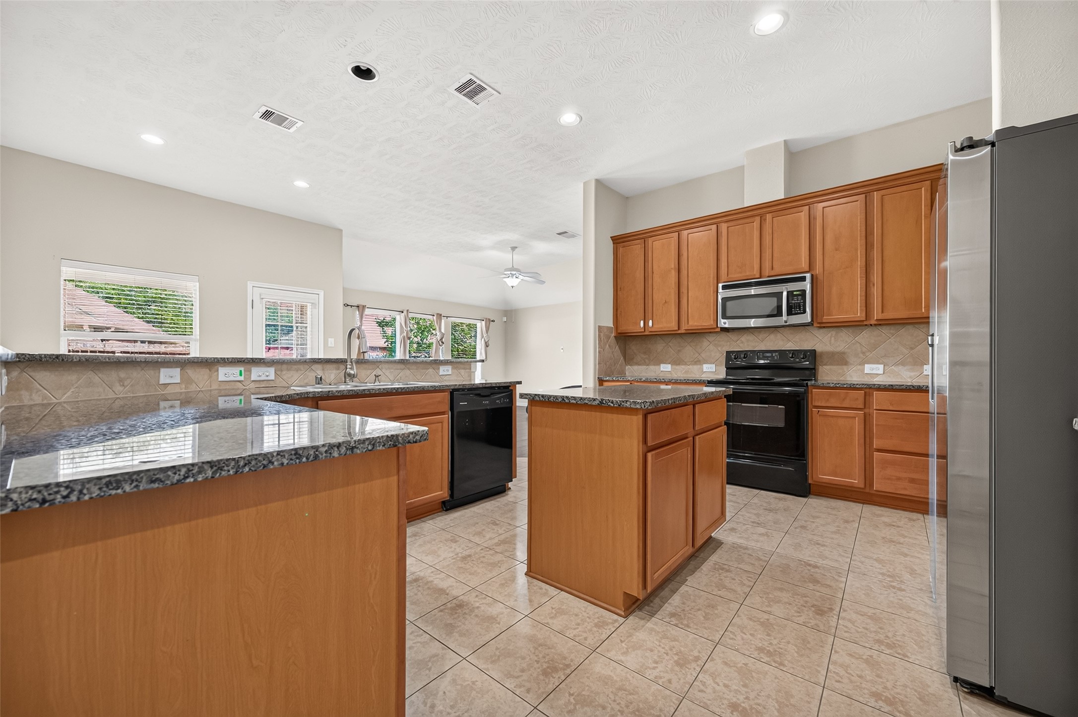 Additional kitchen perspective highlighting the cabinetry, center island, and bright adjoining space.