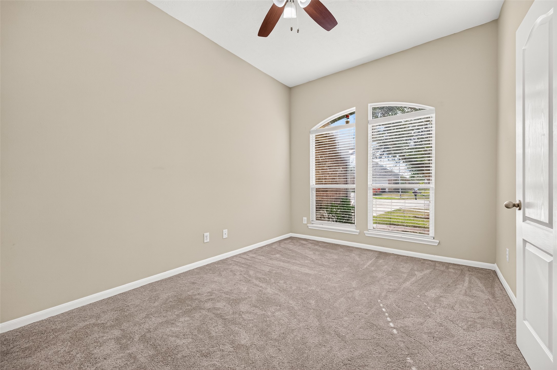 Secondary bedroom featuring a vaulted ceiling, ceiling fan, neutral carpeting, and a window providing natural light.