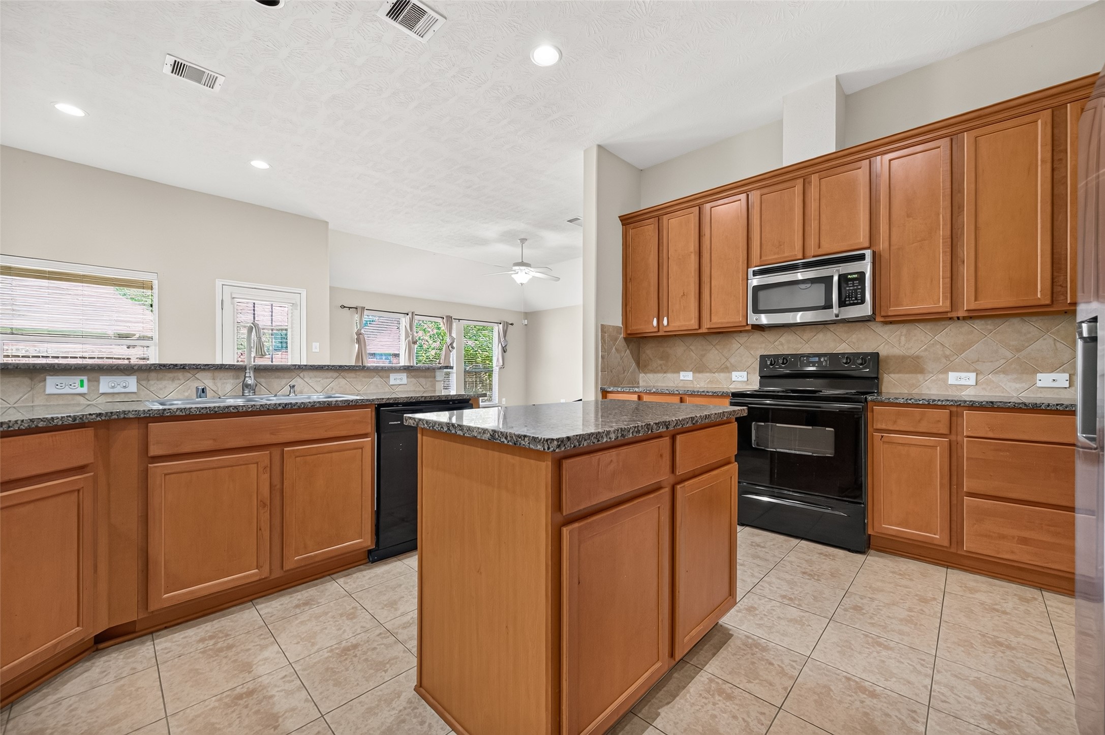 Wide kitchen view showcasing the functional layout, center island, and connection to the surrounding areas.