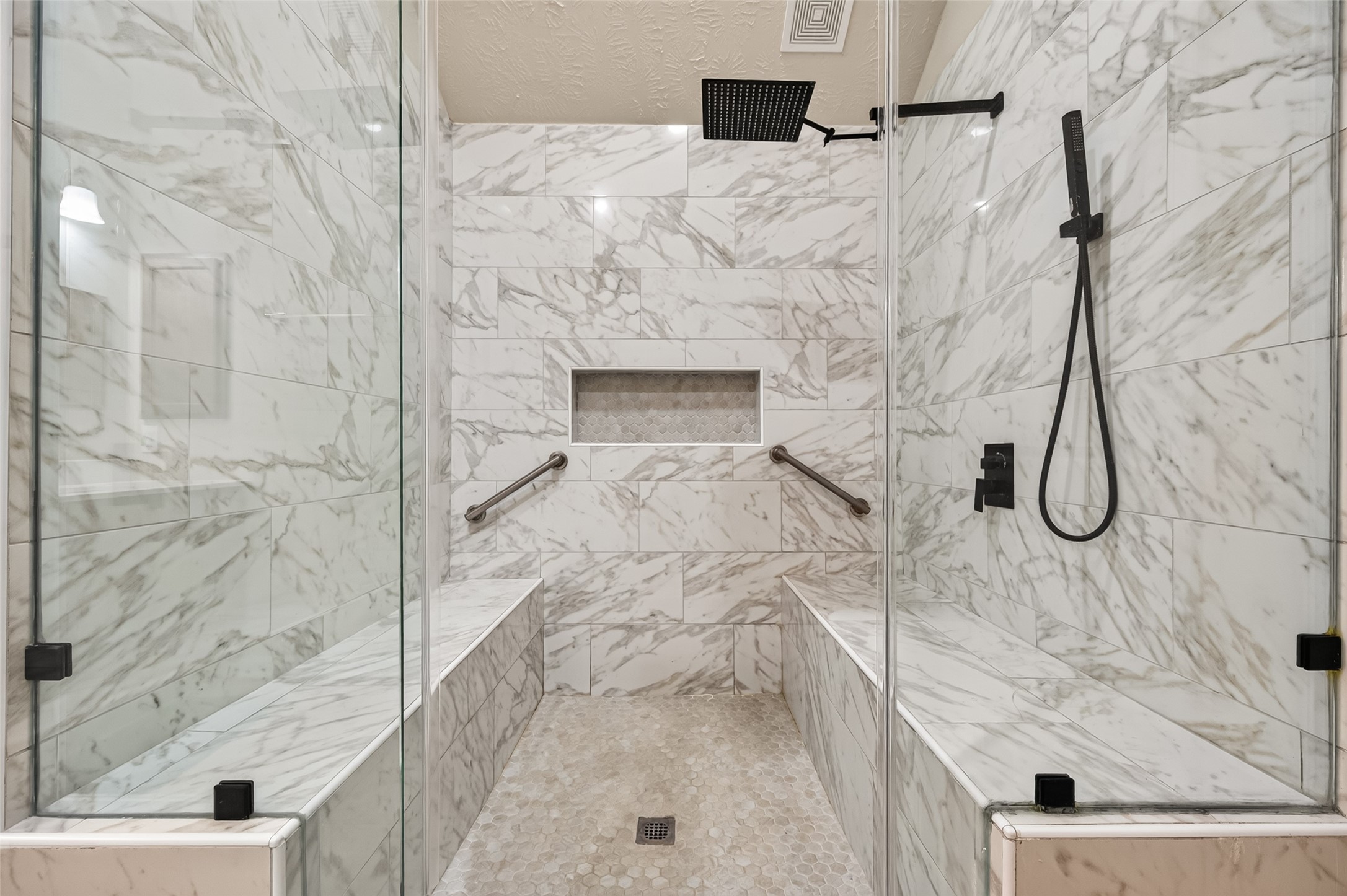 Additional shower view highlighting the tiled surround, built-in niche, and modern shower fixtures.