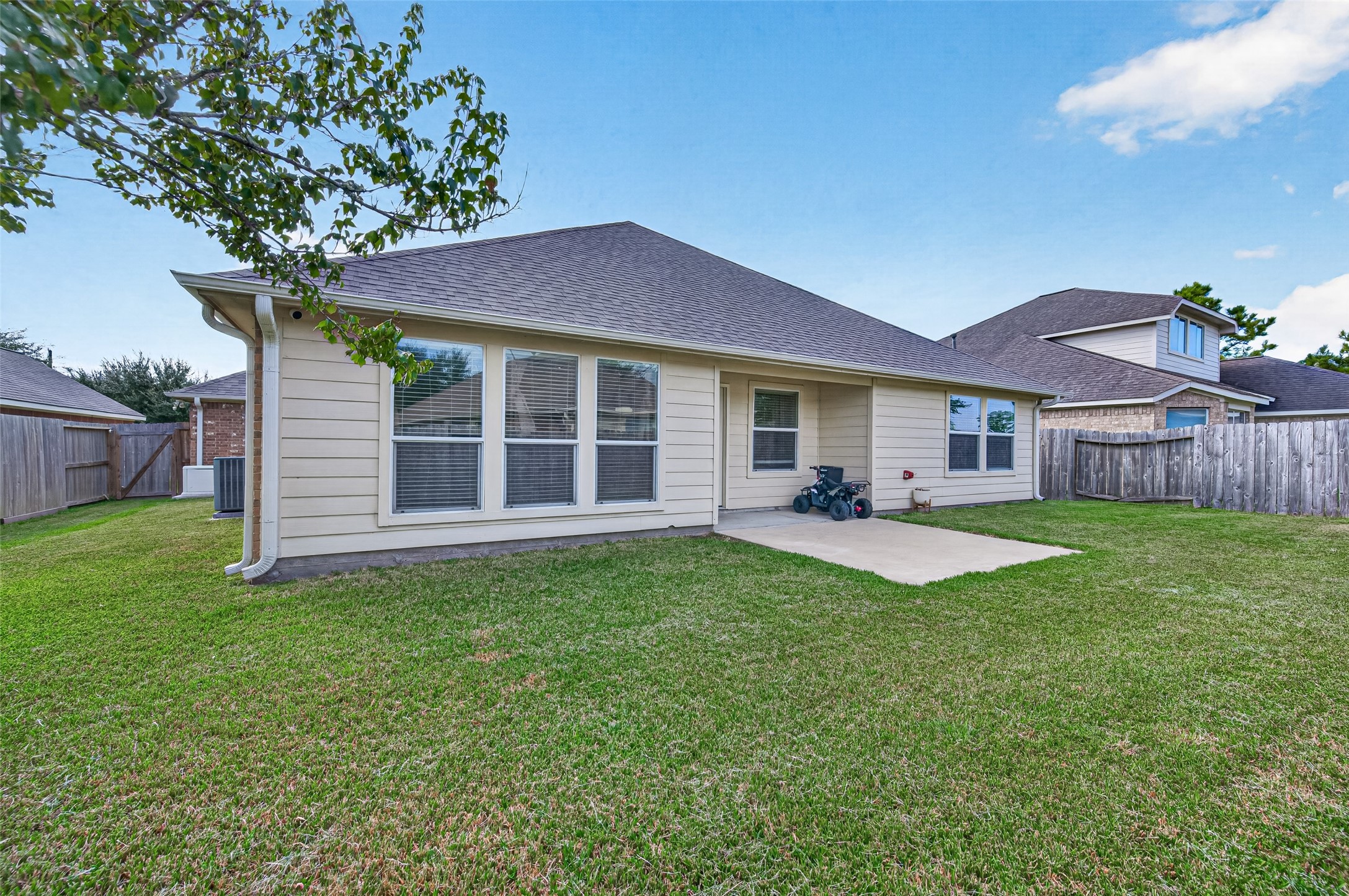 Spacious fenced backyard featuring an open lawn and covered patio area.