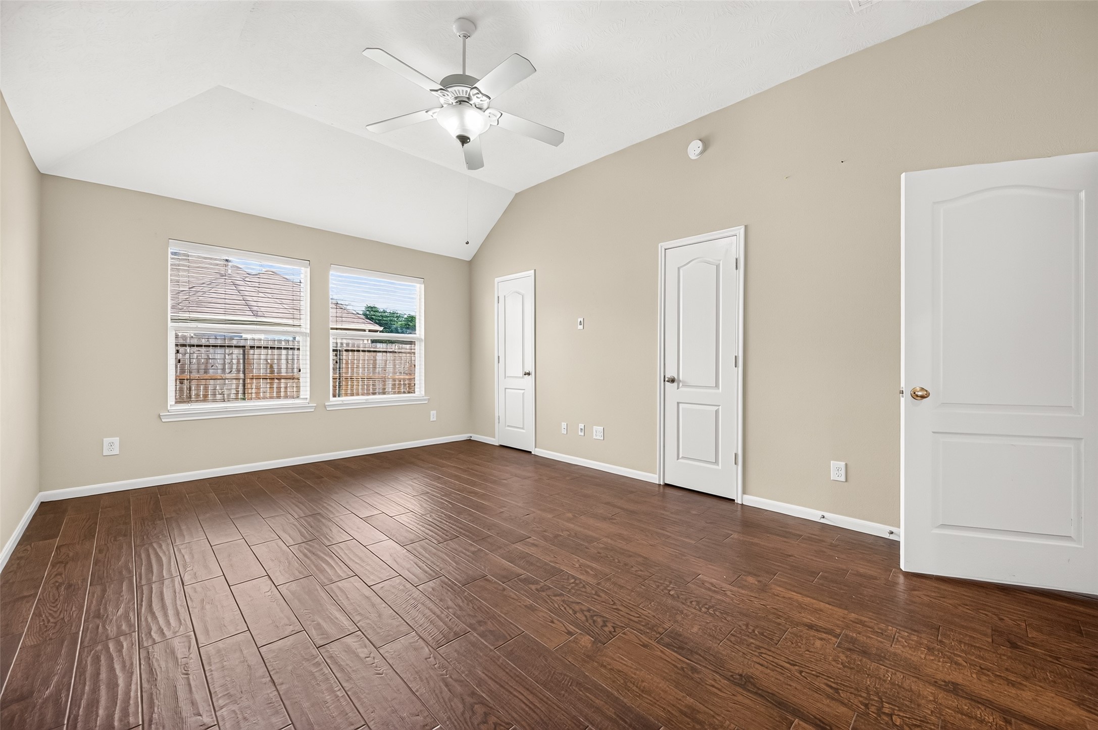 Additional view of the primary bedroom showcasing the wood-look flooring, neutral walls, and backyard-facing windows.