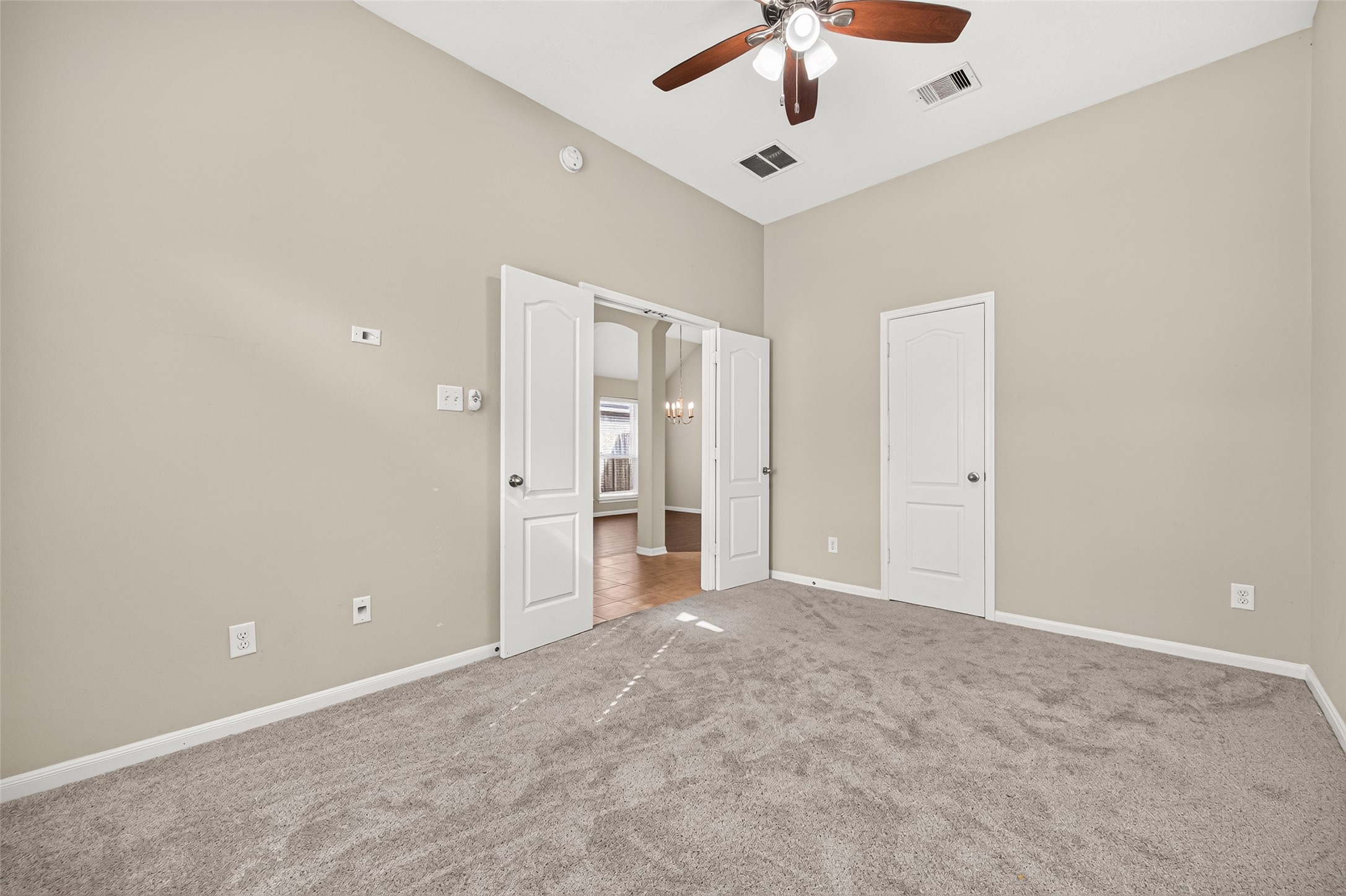 Additional view of the secondary bedroom showcasing its vaulted ceiling, neutral finishes, and adjoining doorway.