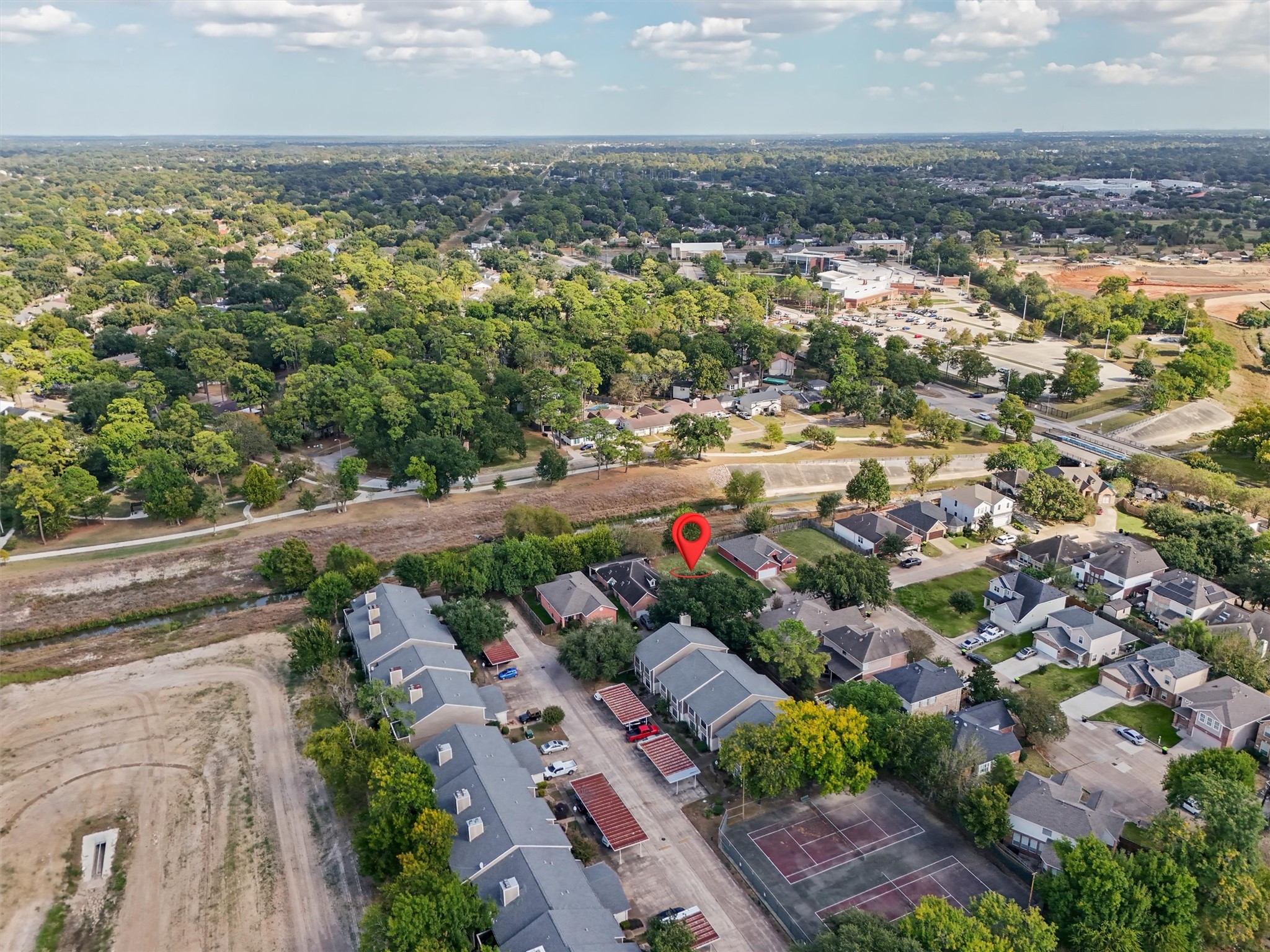 This cleared residential lot offers a wonderful opportunity to enjoy neighborhood living surrounded by mature trees, established homes, and nearby recreational amenities. The aerial view highlights the surrounding green spaces, walking paths, tennis courts, and nearby shopping and commercial areas. With convenient access to local roads and everyday essentials, this homesite offers a great combination of residential charm and accessibility. Your opportunity to build something special starts here!