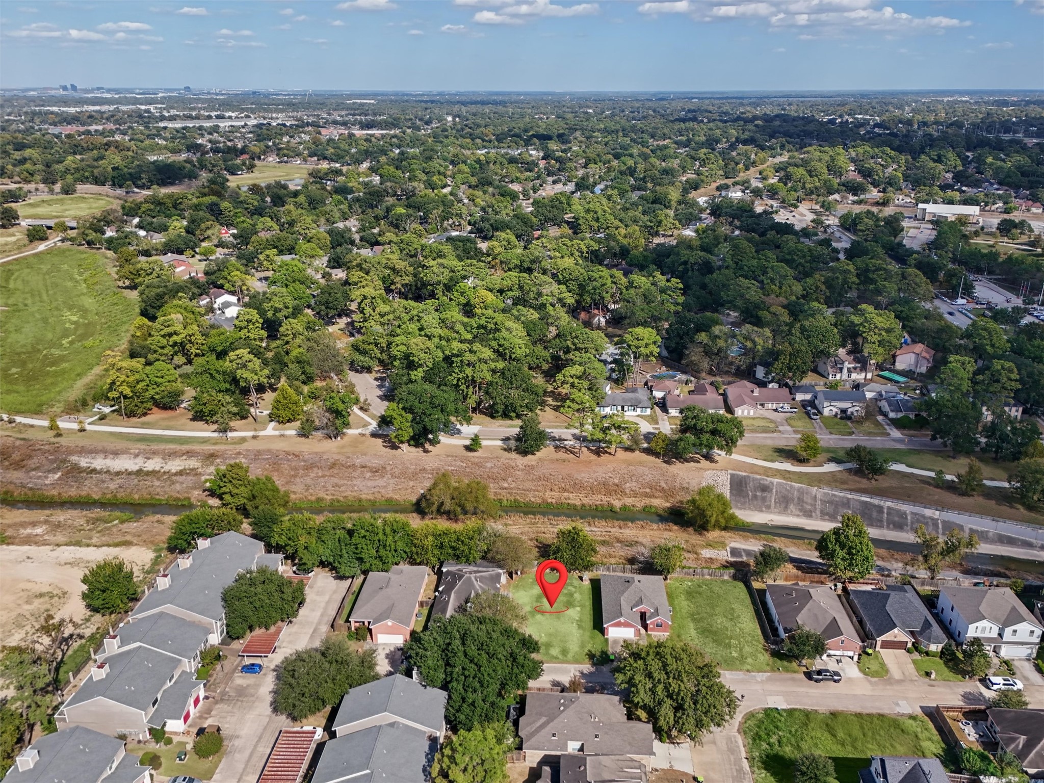 The red arrow highlights this cleared residential lot, offering a rare opportunity to enjoy added privacy with no immediate rear neighbors! Backing to an open greenbelt and waterway, this homesite provides a peaceful setting surrounded by mature trees and established homes.