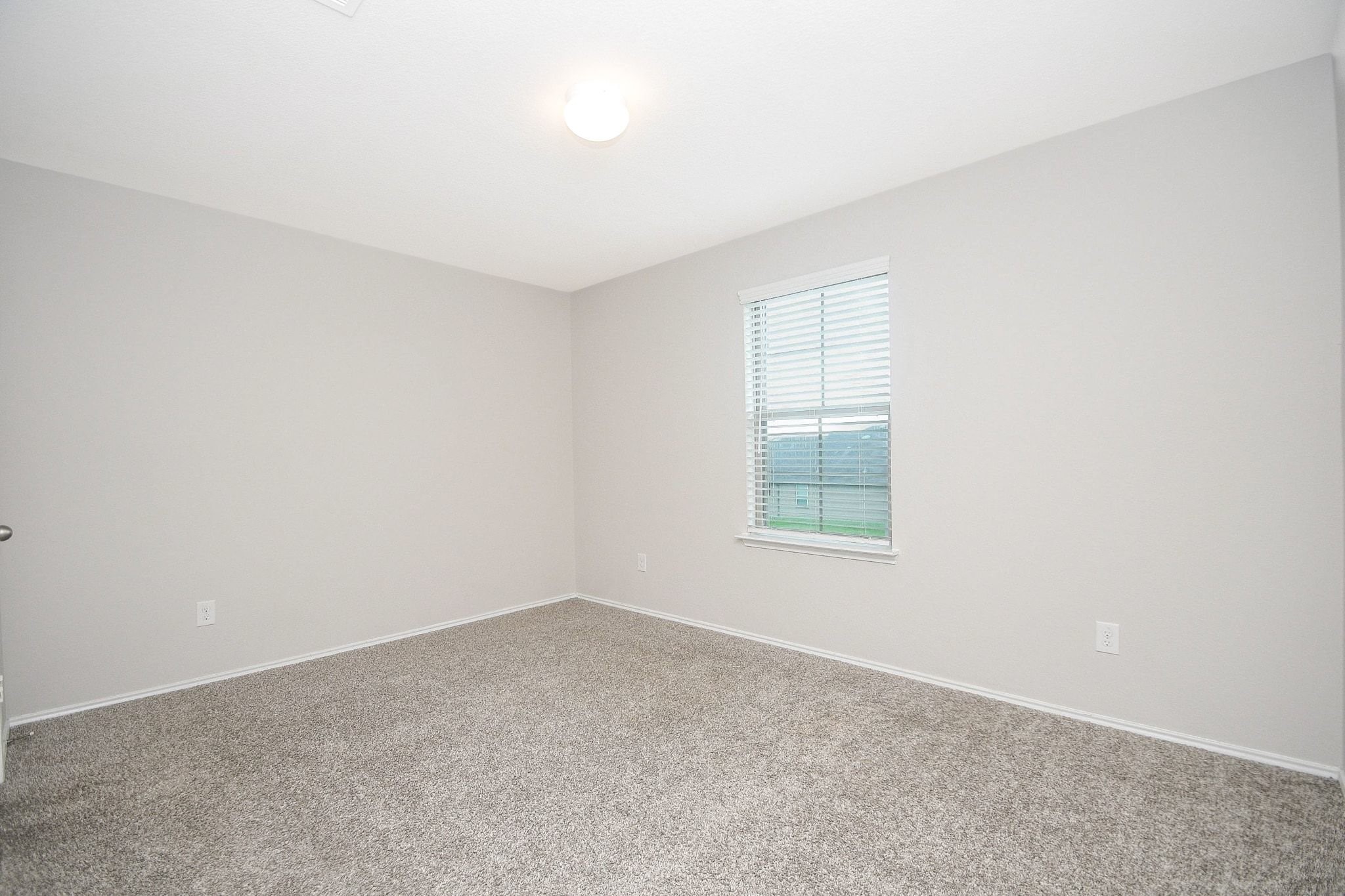 Bright and inviting third bedroom upstairs with soft carpet, neutral walls, and a large window for natural light.