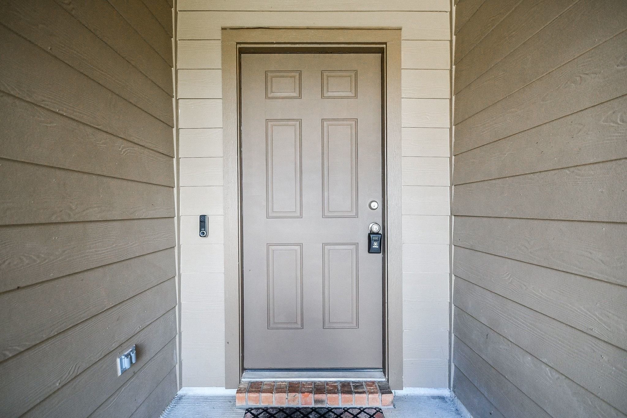 Inviting entryway with a sturdy door, accented by clean, modern siding and a welcoming porch light.