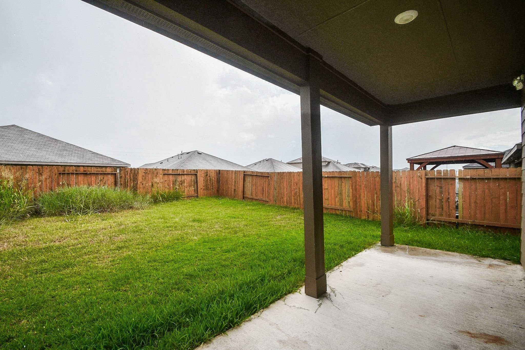 Step into a spacious backyard featuring a covered patio and a wooden fence, perfect for outdoor relaxation and privacy.