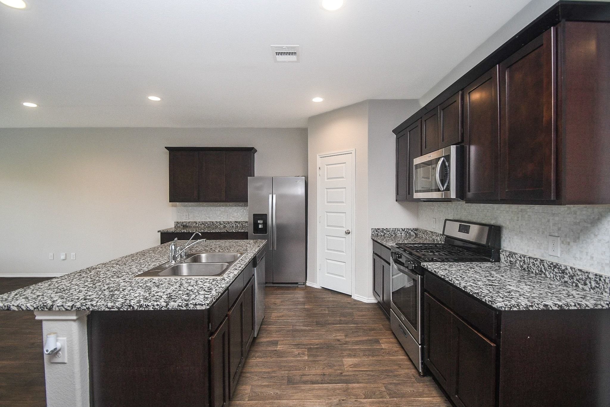 Spacious modern kitchen featuring granite countertops, stainless steel appliances, and rich dark wood cabinetry, perfect for culinary enthusiasts.