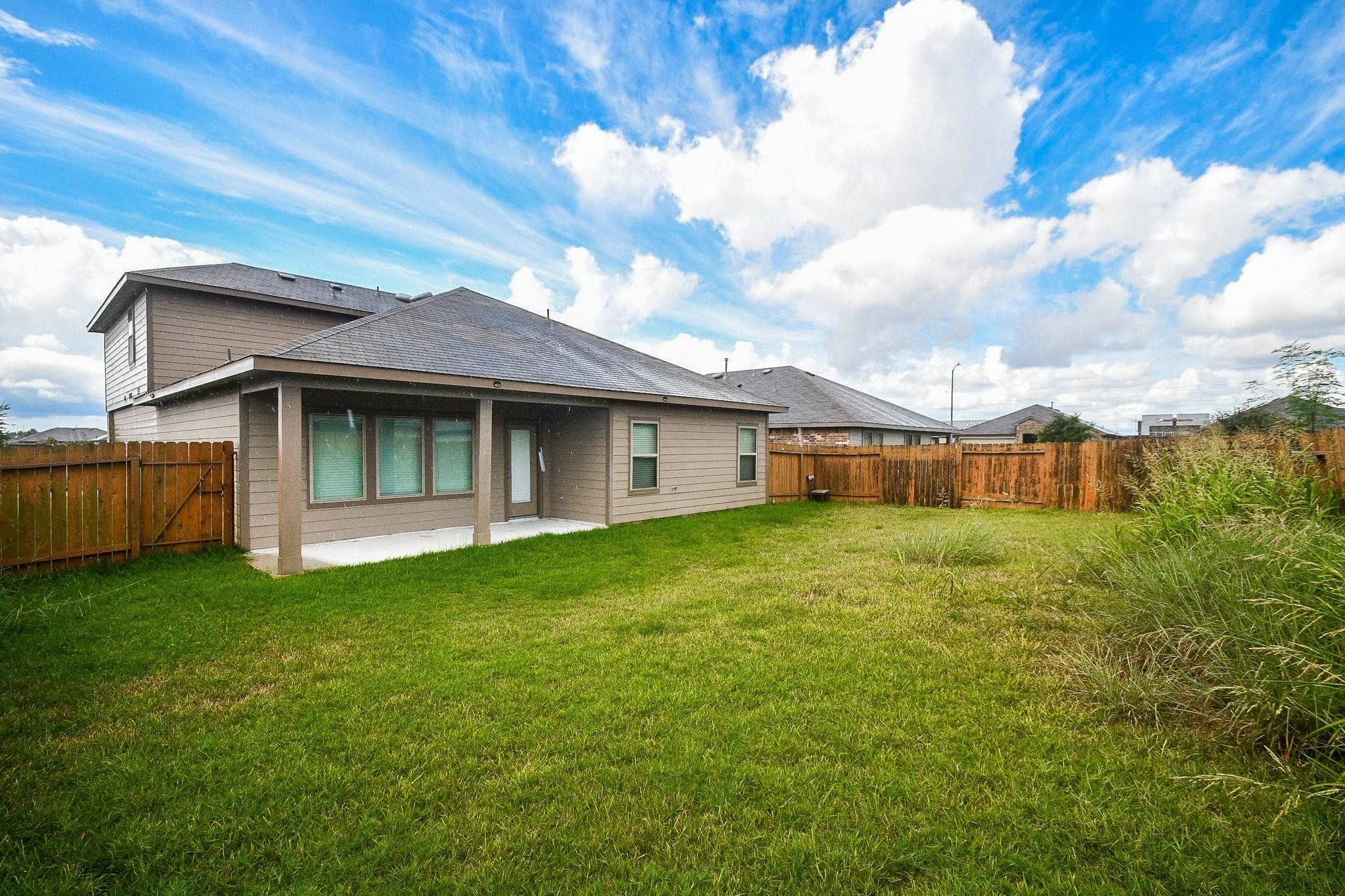 Spacious backyard with a covered patio, perfect for outdoor relaxation and entertaining, surrounded by a wooden privacy fence.