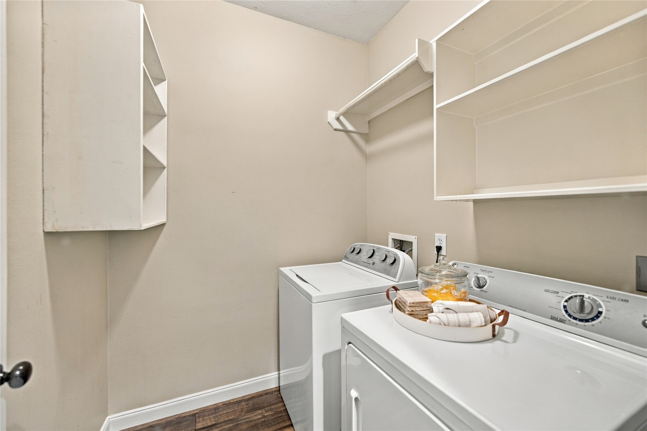 The laundry room is located conveniently off the kitchen. Complete with washer and dryer for your use, it contains hanging space and plentiful open shelving.
