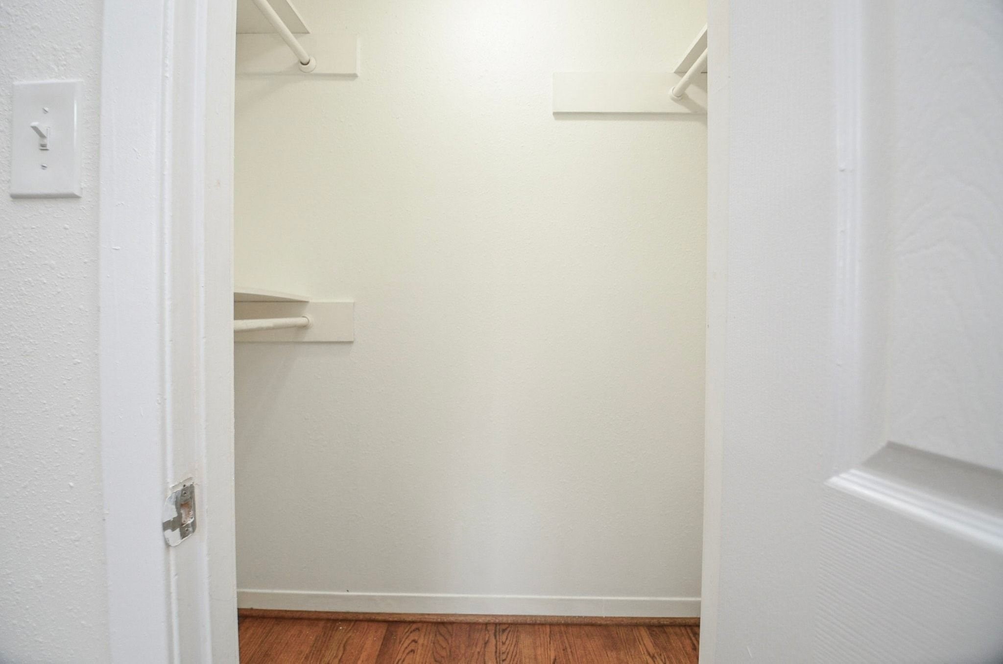 Walk-in closet with built-in shelving on multiple sides.