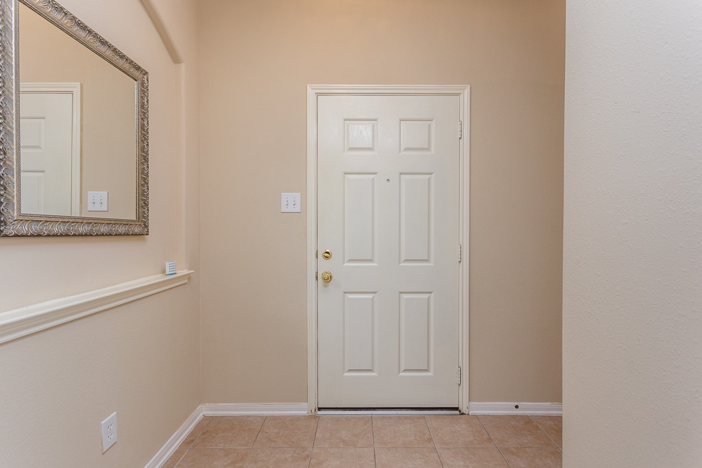 Inviting entryway with a classic white door, neutral walls offering a warm welcome.