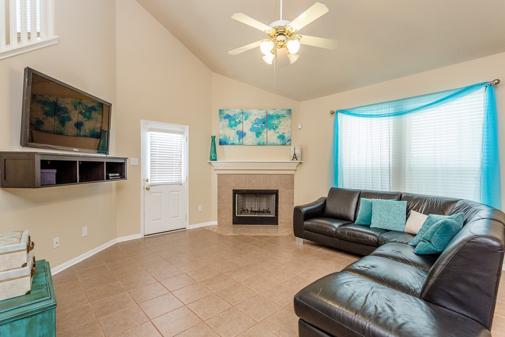 Cozy fireplace, and large sectional sofa, complemented by abundant natural light and elegant tile flooring.