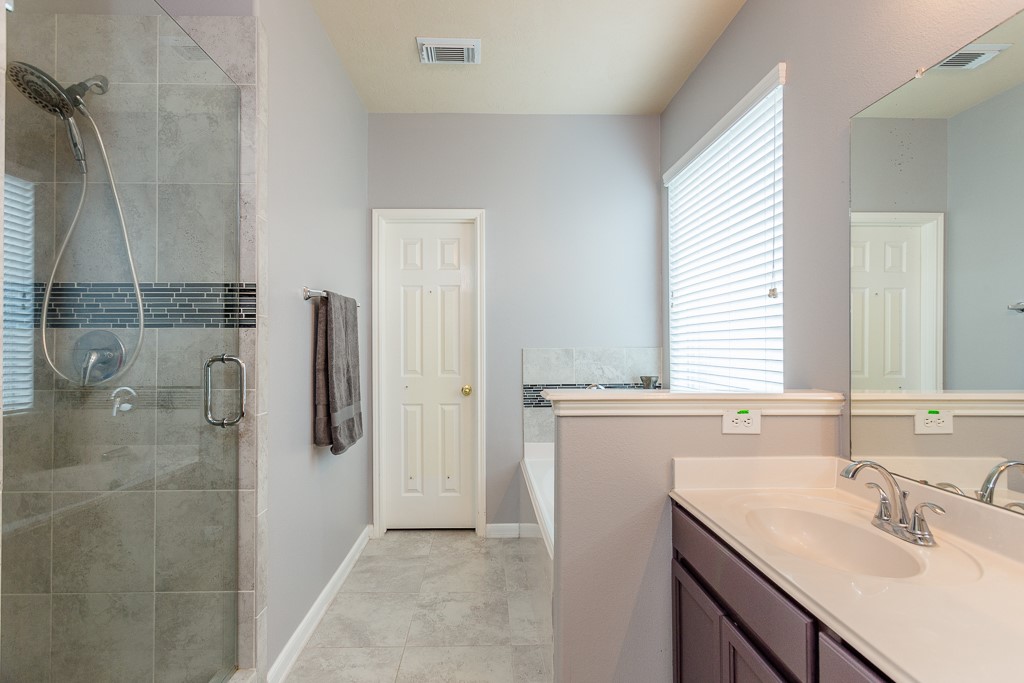 Modern bathroom featuring a sleek glass-enclosed shower, dual sinks with elegant fixtures, and a relaxing soaking tub.