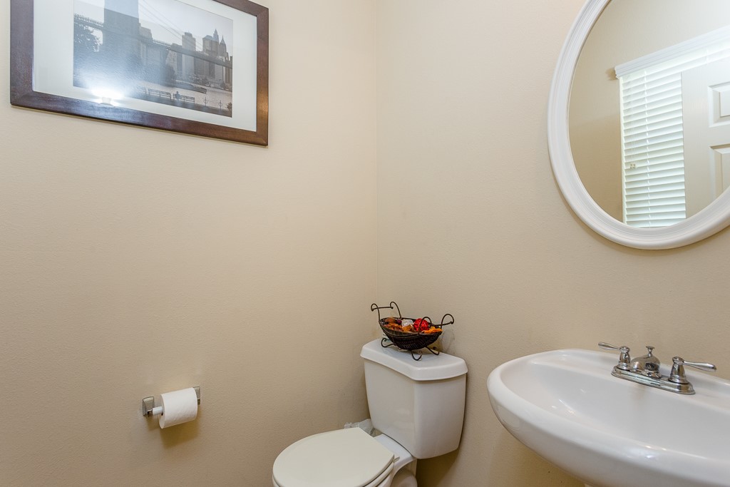 Charming half-bathroom featuring a sleek pedestal sink.