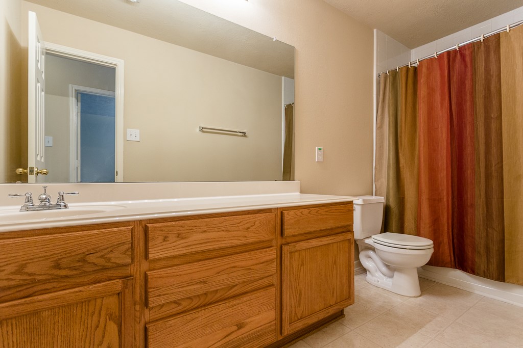 Upstairs bathroom featuring a large mirror, elegant wood cabinetry.
