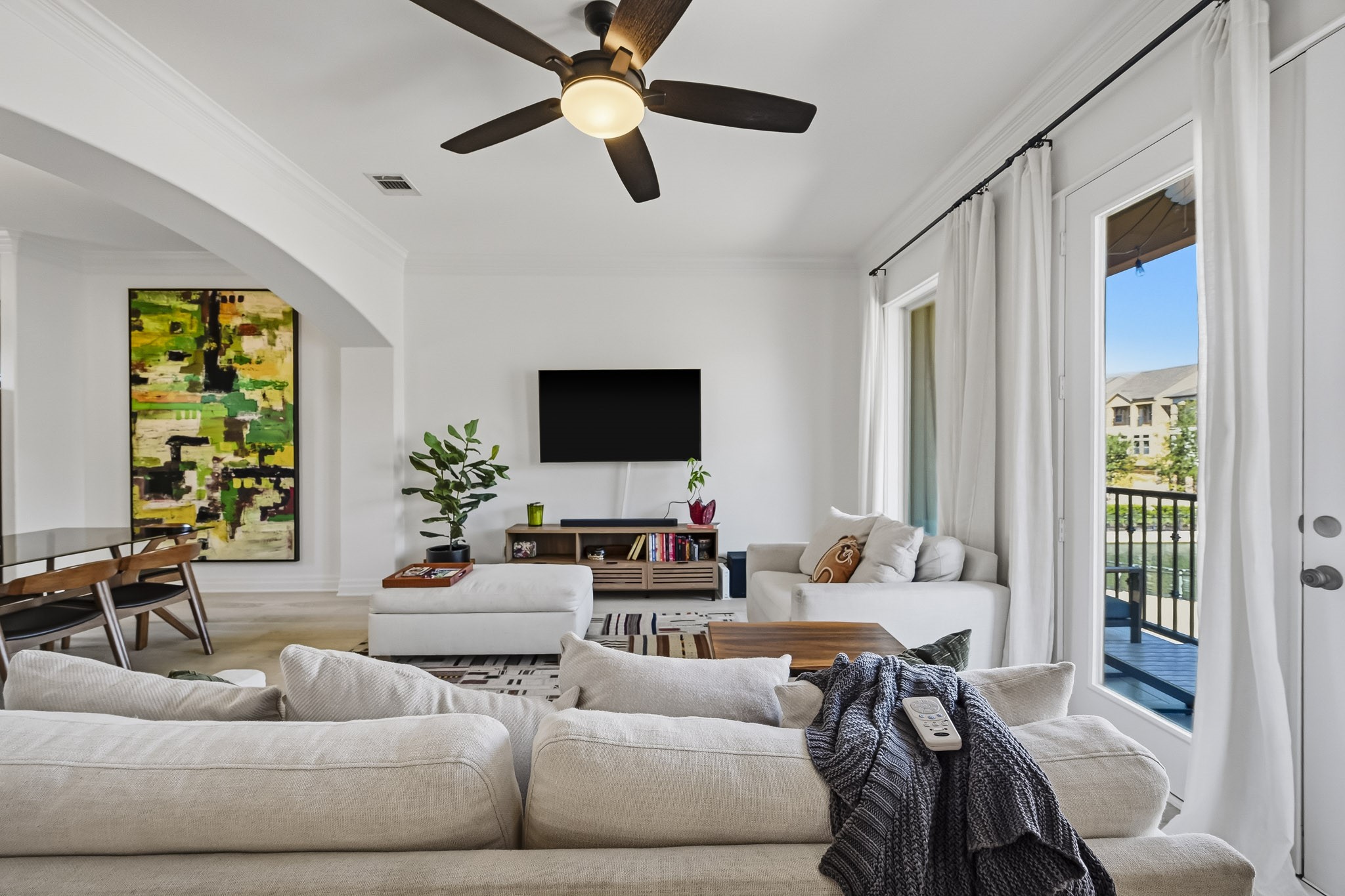 Elegant living area with abundant natural light, featuring a cozy seating arrangement, and stylish dcor. A large window offers a view of the outdoor space, enhancing the room's inviting atmosphere.