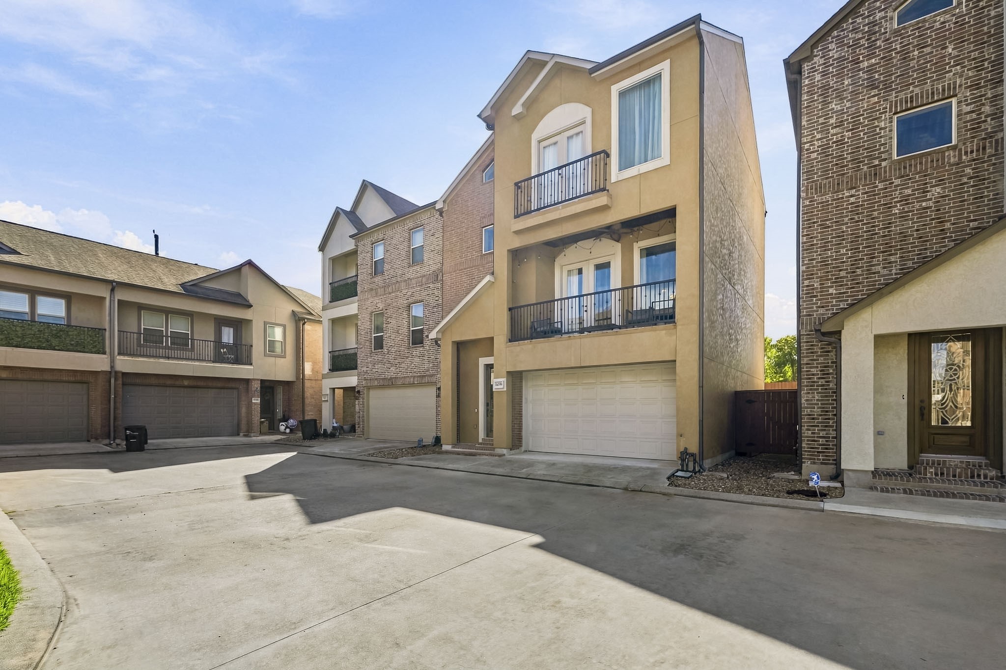 Contemporary three-story townhouse with a two-car garage, featuring a charming balcony and a blend of modern and traditional architectural elements.