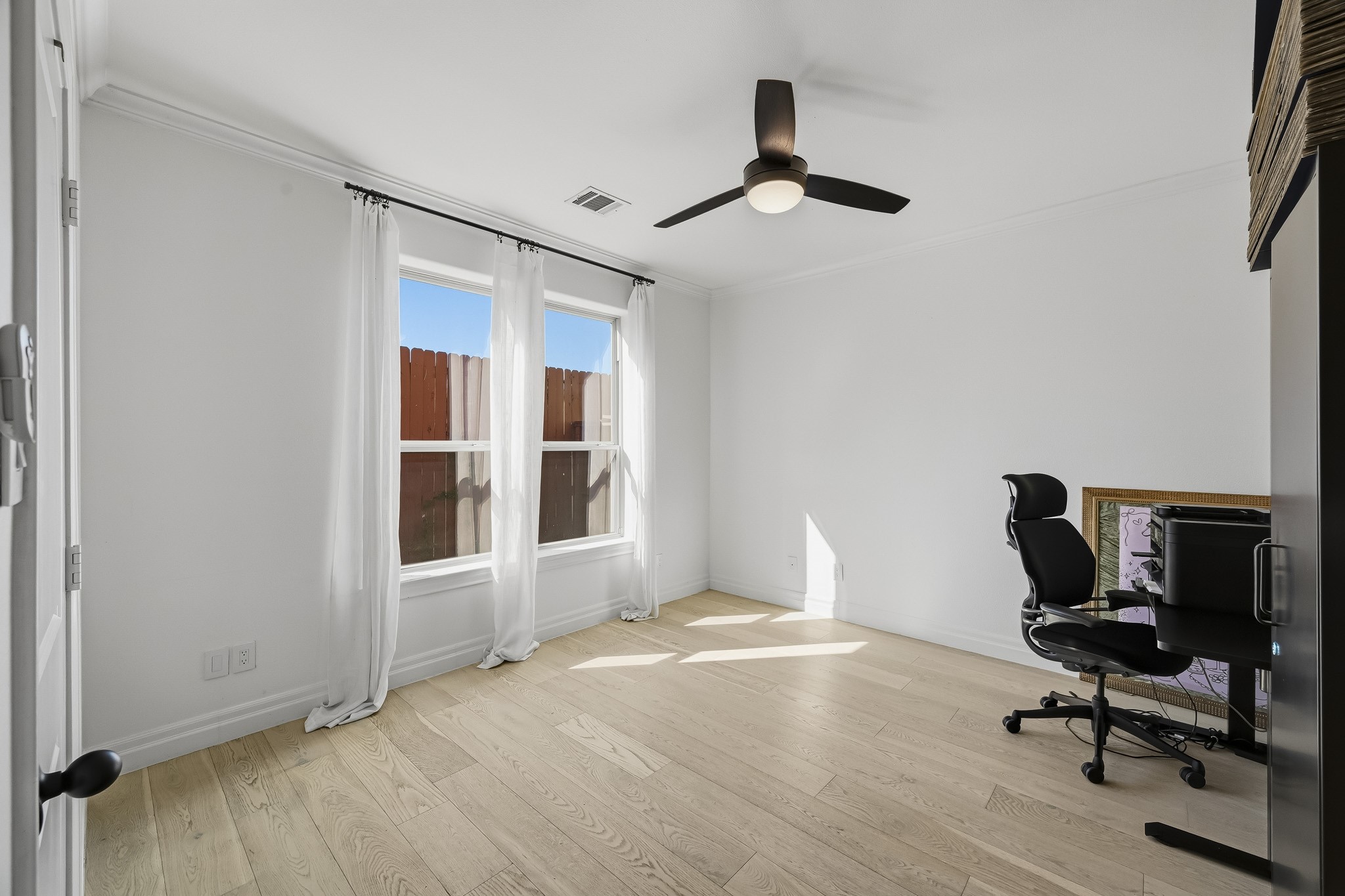 Bright and inviting room with large windows, light wood flooring, perfect for a home office or study space.