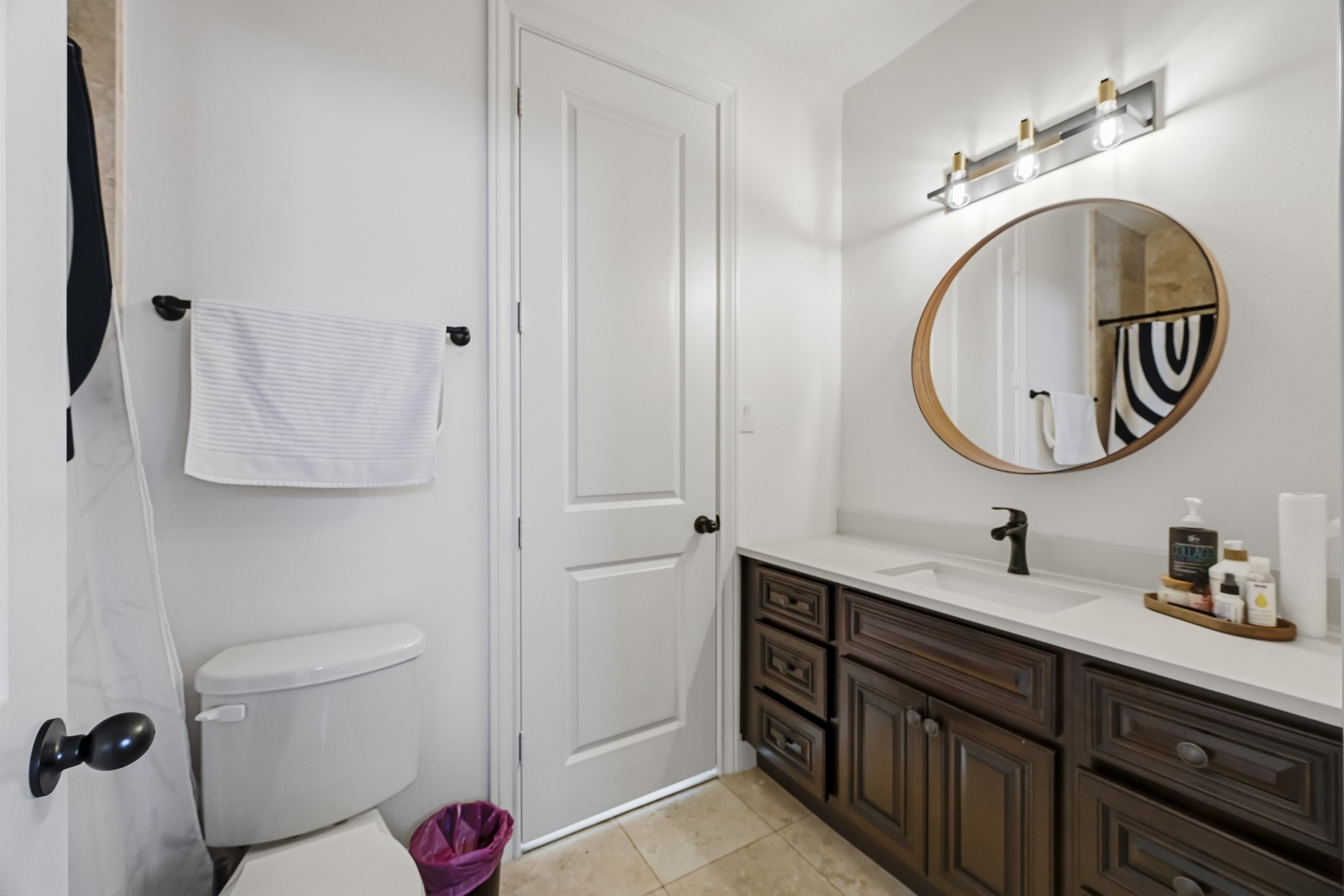 Elegant bathroom featuring a stylish vanity with a round mirror, modern lighting, and ample storage space.