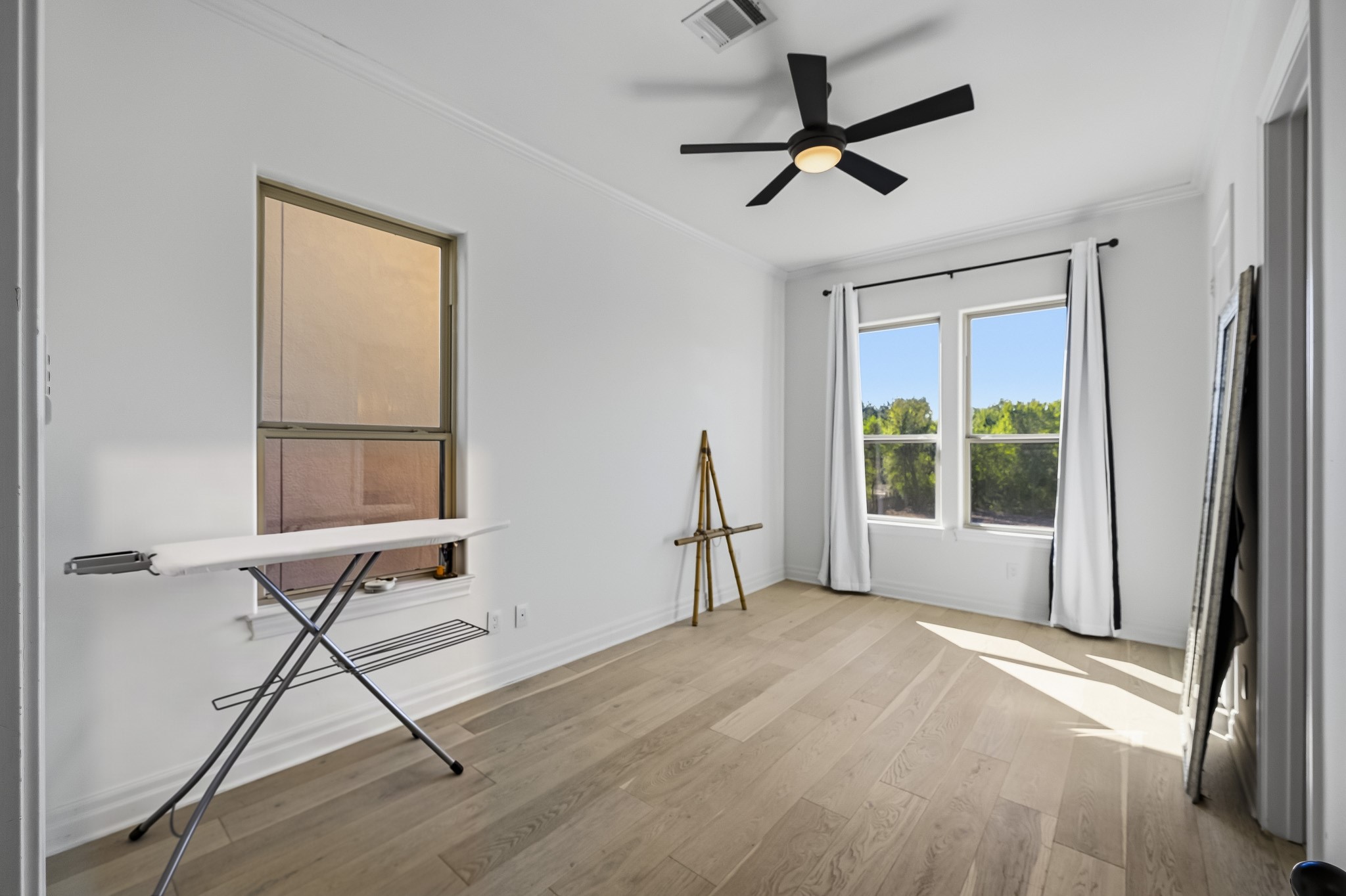Bright and airy room featuring large windows, sleek wood flooring, perfect for a creative workspace or cozy retreat.