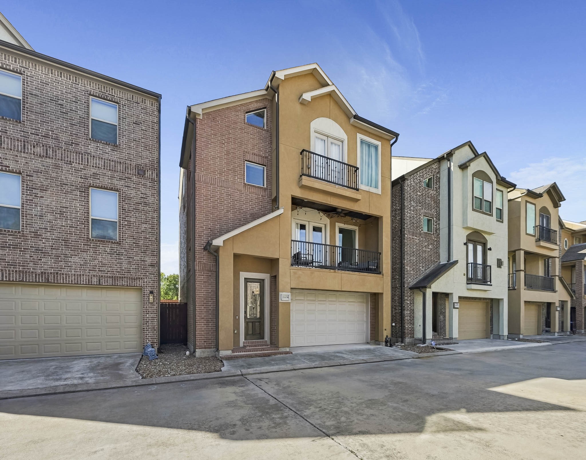 Modern three-story townhouse with a charming balcony, two-car garage, and inviting entryway, nestled in a well-maintained community.