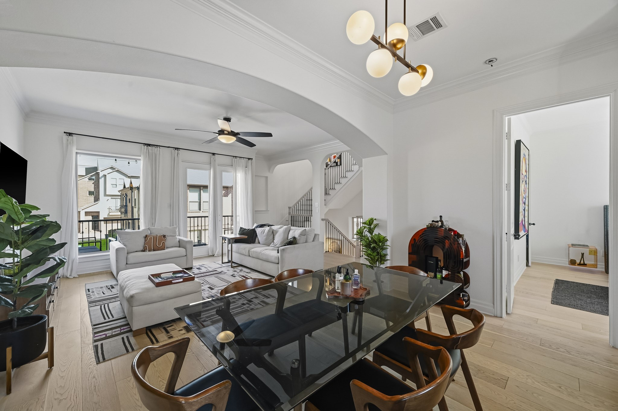 Spacious open-concept living area features elegant hardwood flooring, abundant natural light from large windows, and a stylish dining space with modern lighting, perfect for entertaining and relaxation.