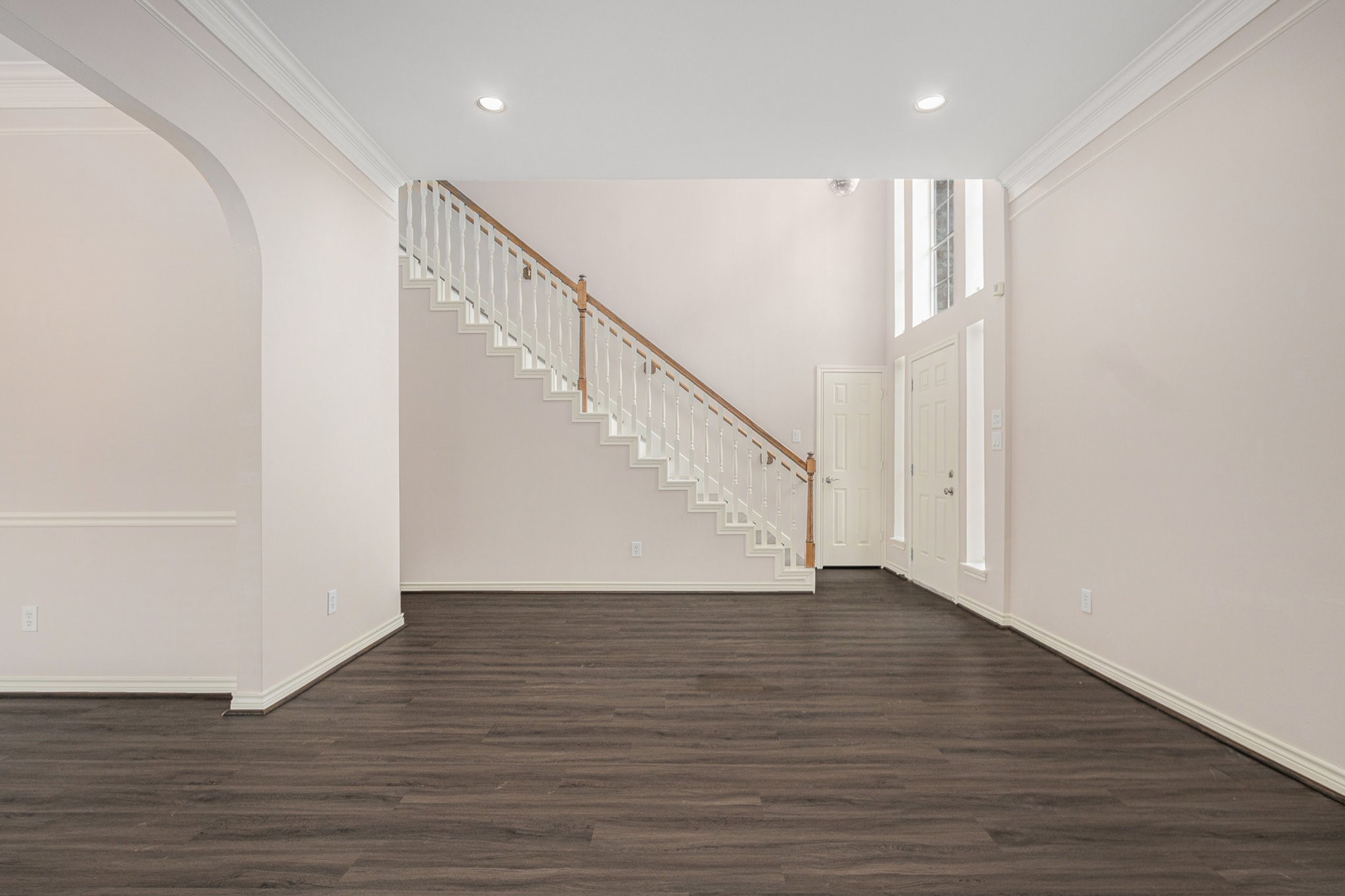 This spacious area features high ceilings and elegant wood flooring, with a beautiful staircase leading to the upper level. Natural light flows through large windows, enhancing the entryways welcoming feel.