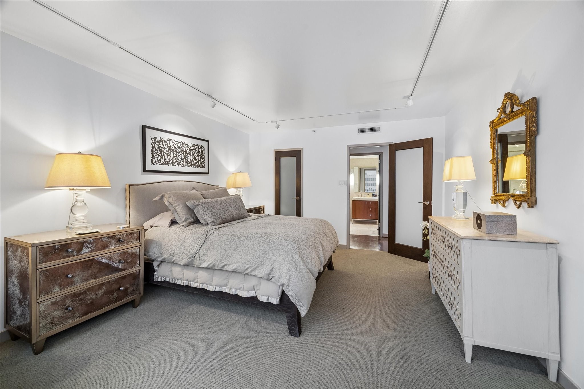 Reverse bedroom view shows the route toward the adjoining hall and bath. Frosted glass door inserts and track lighting continue the interior details found throughout the residence.