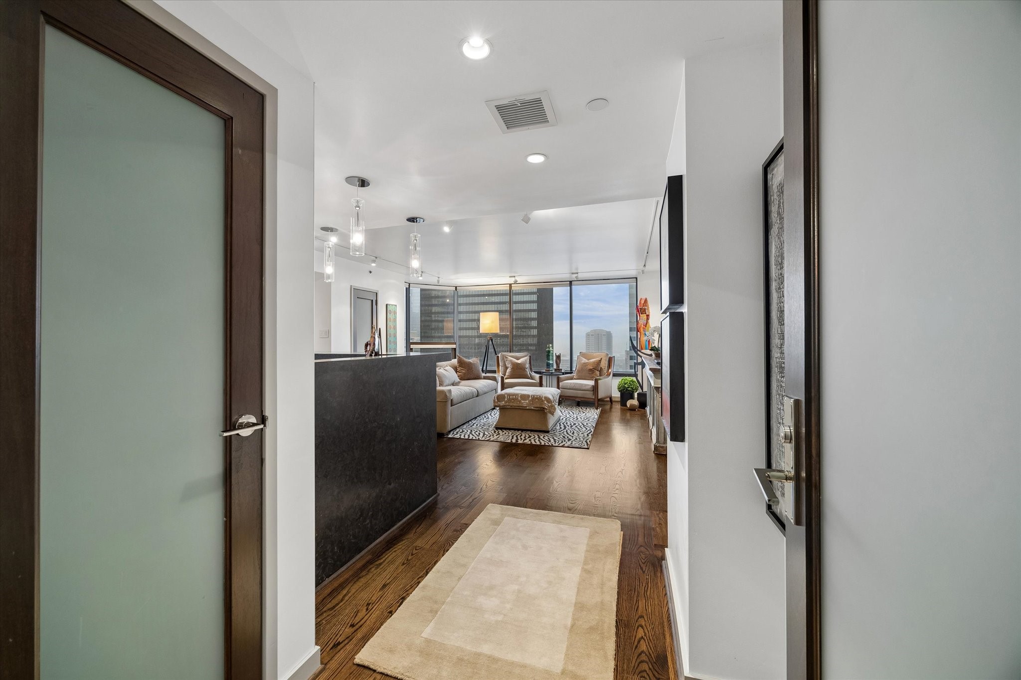 Entry corridor leads directly into the living area, with frosted glass door inserts carrying light between interior spaces. Nearby closet storage keeps everyday essentials close to the entrance.