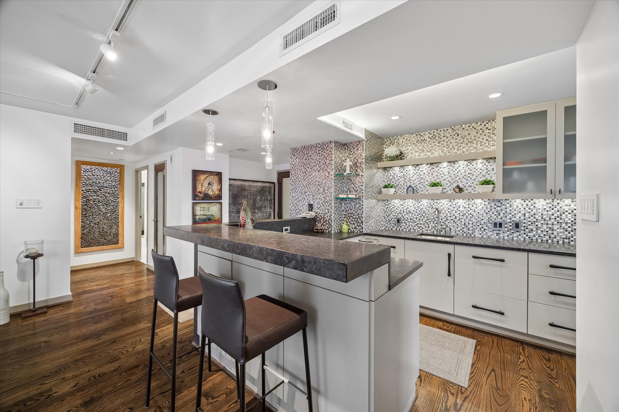 Glass front upper cabinets and open shelving combine enclosed storage with easy access to frequently used items. Counter space wraps around the kitchen, keeping preparation areas connected to the breakfast bar.