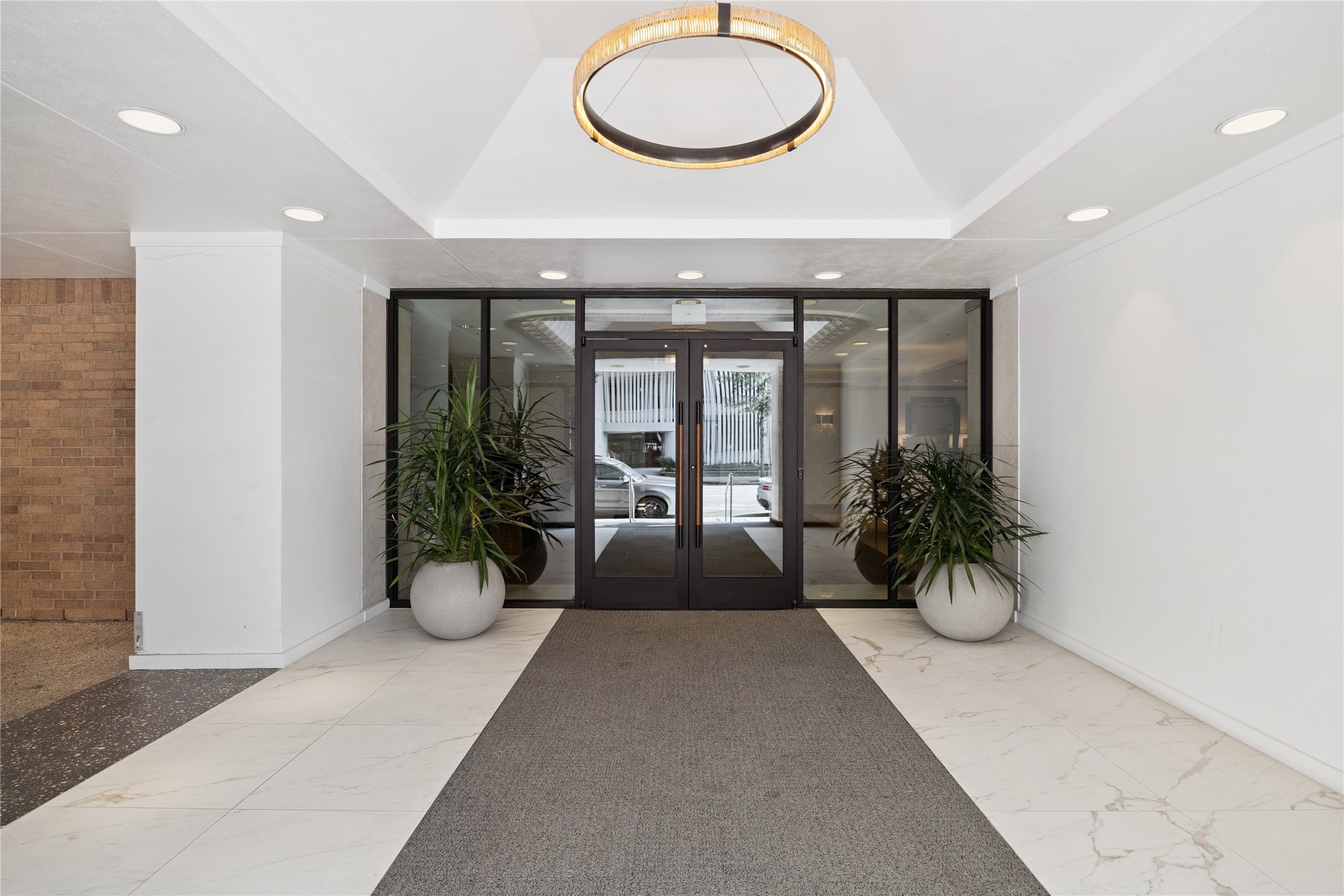 Residential vestibule creates a transition from the exterior entrance to the lobby. Glass doors and overhead lighting define the route into the building.