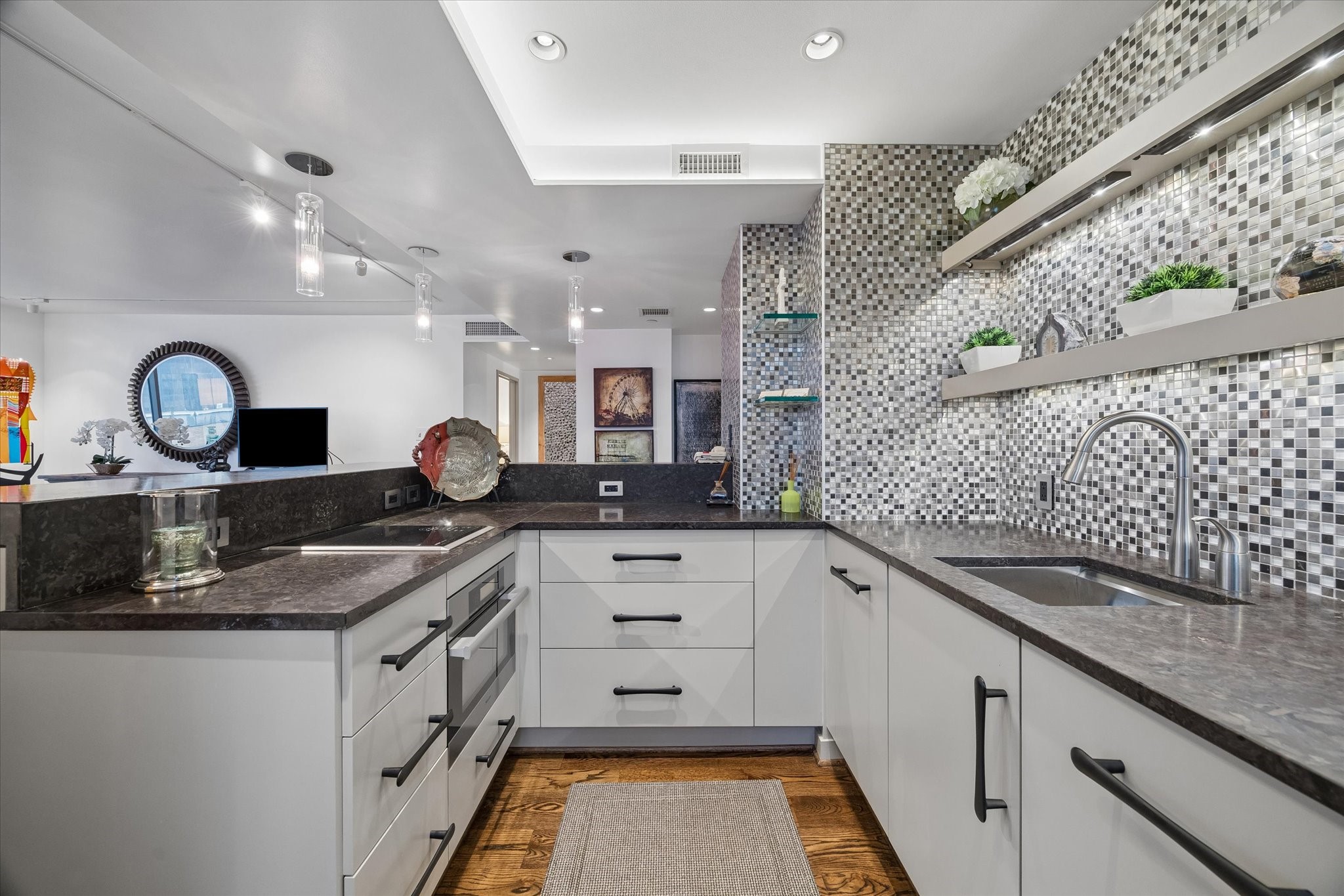 U shaped counters organize the kitchen around a central workspace. Lower drawers, cabinets and open shelves provide storage beside the sink and cooking area.