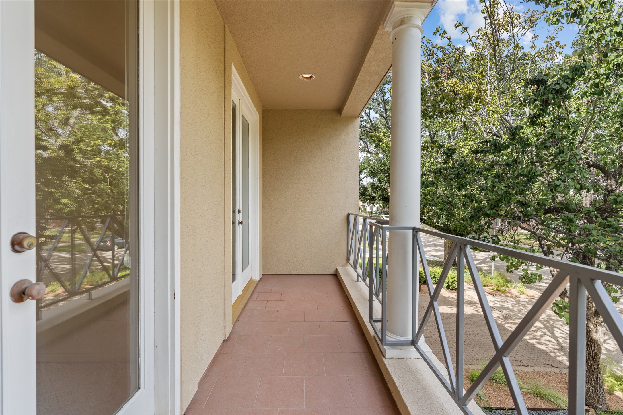 Charming front balcony off bedroom with elegant railings and a cozy outdoor space overlooking lush greenery, perfect for relaxation or entertaining.