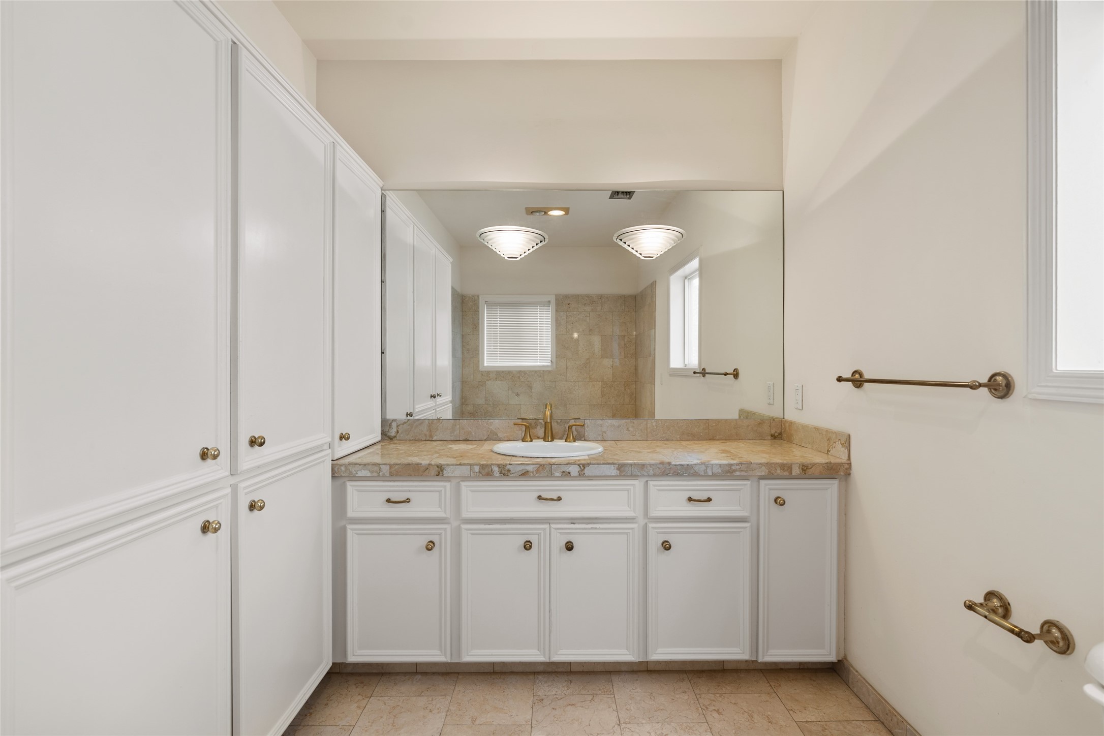 One of 2 primary spacious bathrooms, this one featuring a soaking tub with marble countertops, ample cabinet storage, and a large mirror enhancing natural light.