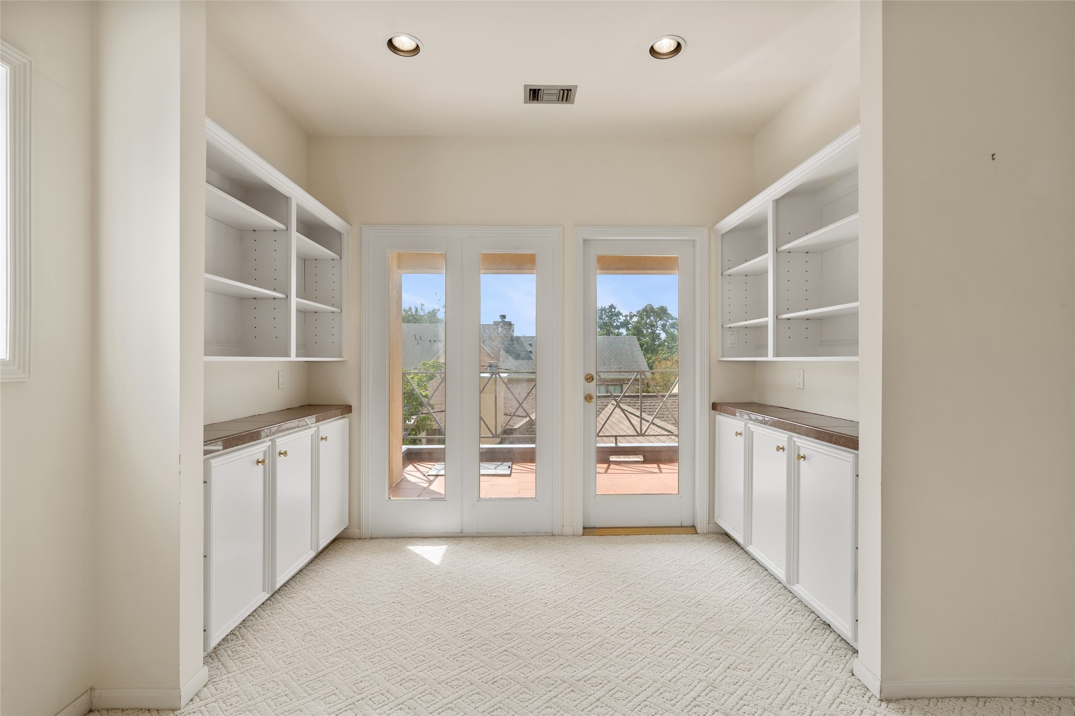 Bright and airy sitting area in the primary bedroom featuring built-in shelving and cabinetry, leading to a balcony. Ideal for a cozy nook or home office.