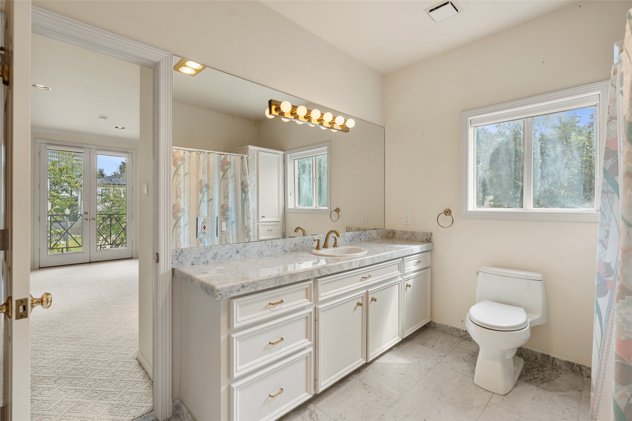 Large secondary bathroom featuring a spacious vanity with marble countertops.